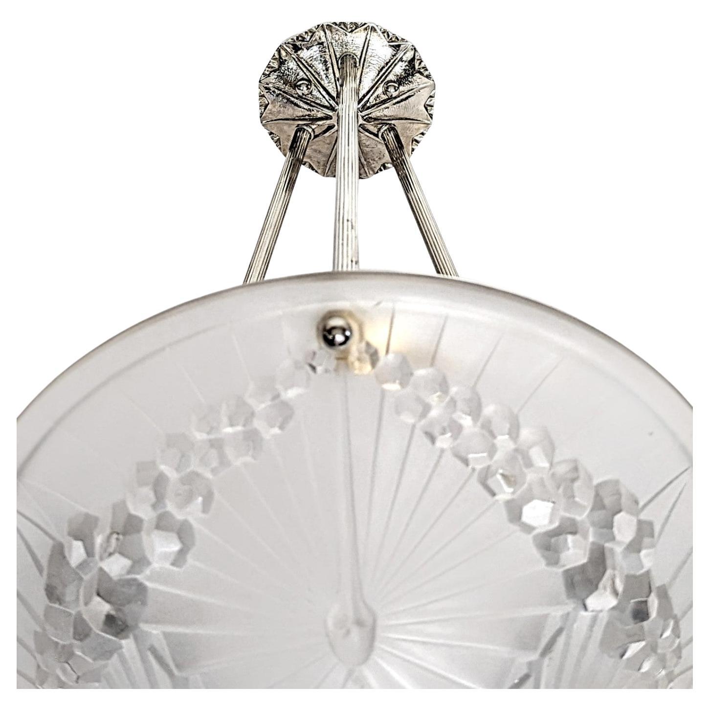 A French Art Deco pendant chandelier by the French artist “Charles Schneider“ in great condition. Clear frosted molded glass shade with intricate flowers and geometric polished motif details are held by three ribbed rods with a matching canopy. The