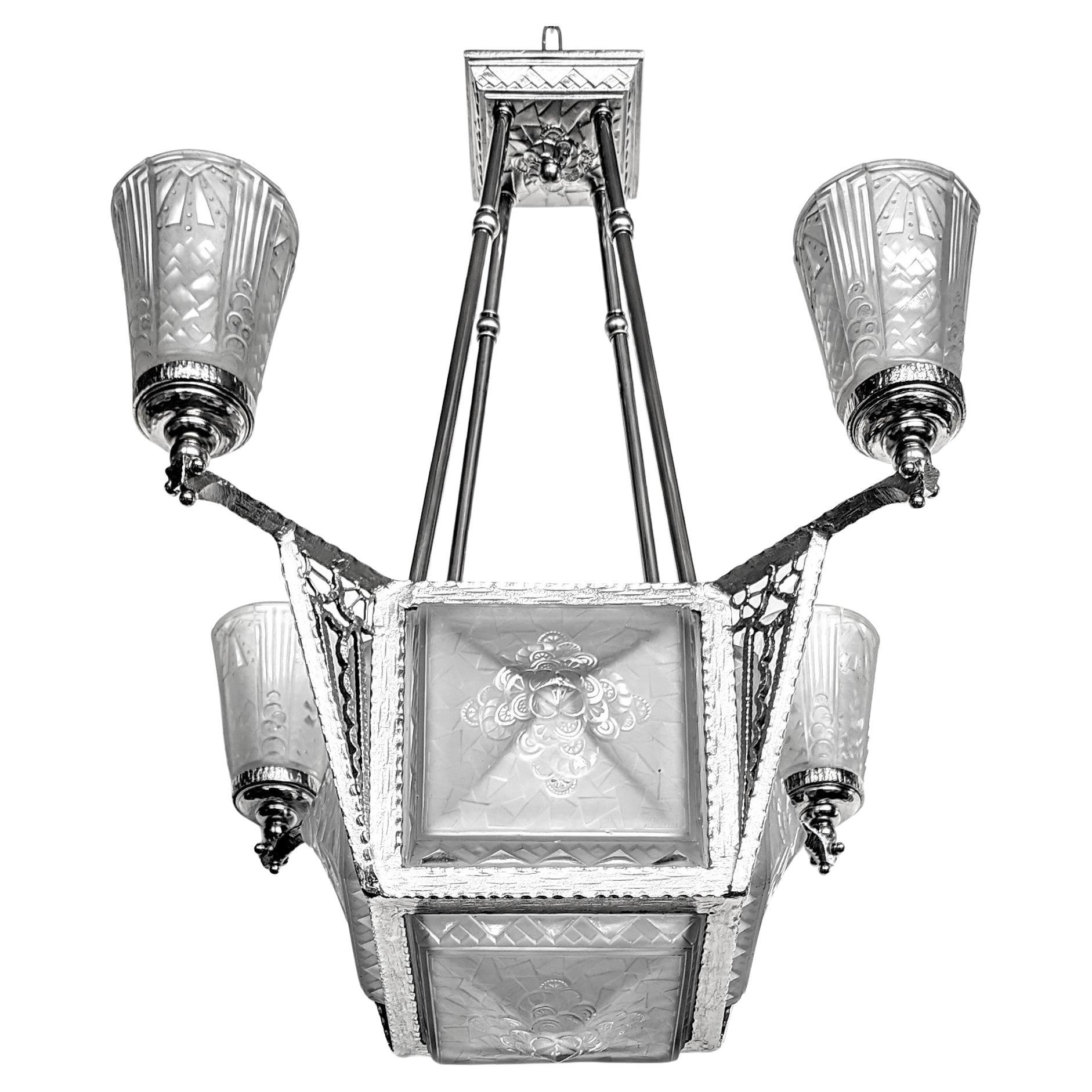 A gorgeous French Art Deco chandelier by Muller Freres in great condition. The chandelier consists of five square shades. Four on each side, and one in the bottom with 4 matching tulipes. In a clear frosted glass with geometric motifs. Mounted on a