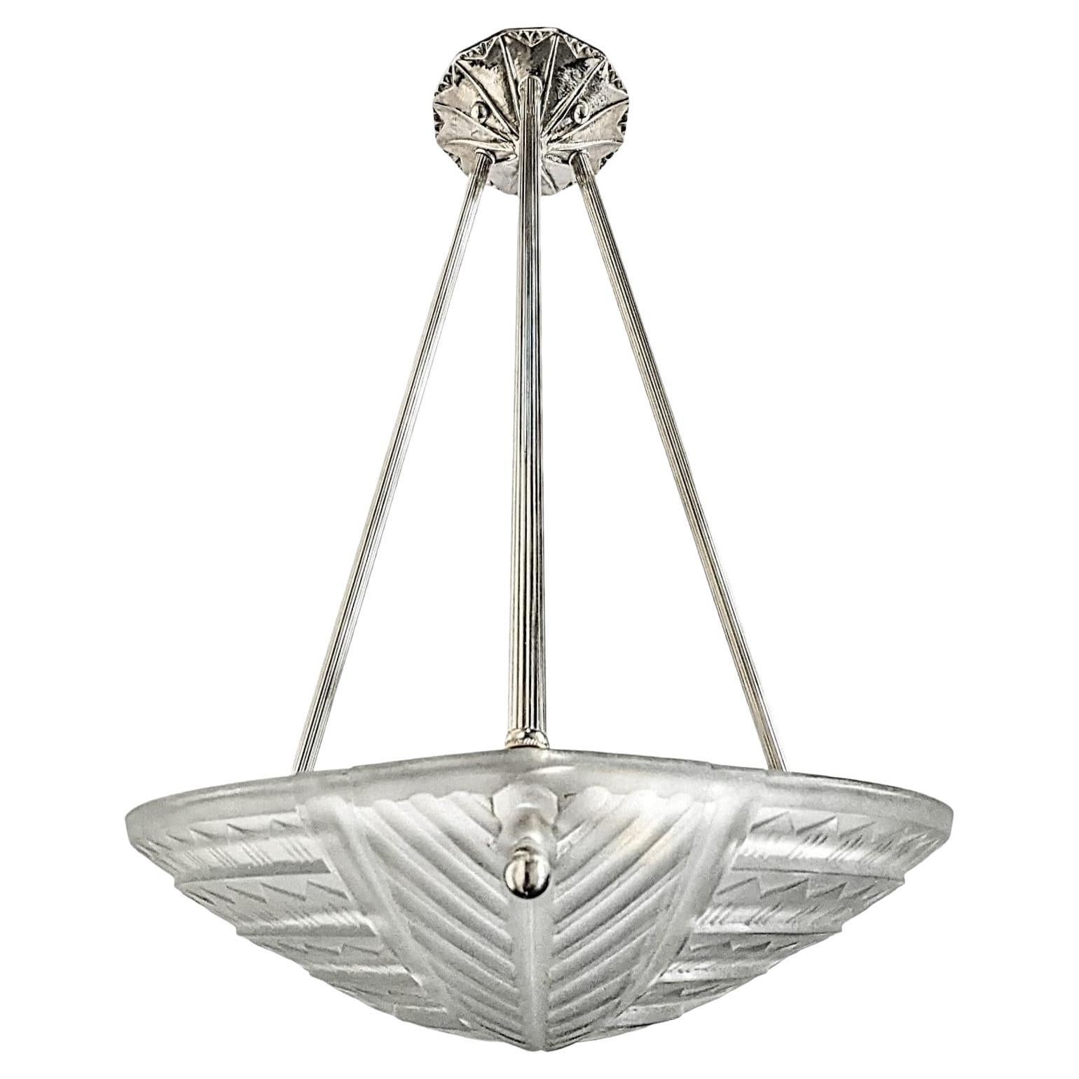 A French Art Deco pendant chandelier by the French artist “Noverdy“ in good condition. Clear frosted molded glass shade with intricate geometric polished motif details is held by three ribbed rods with a matching canopy. The fixture has been