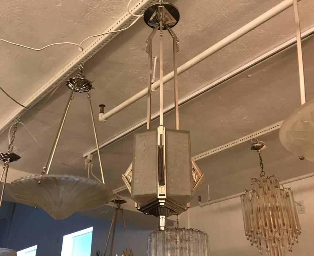 French Art Deco chandelier. Having three triangular clear frosted glass panels with over flowing floral and Deco motif details. Supported by matching layered multi-tiered, geometric design silver bronze frame. Has been re wired for American use.