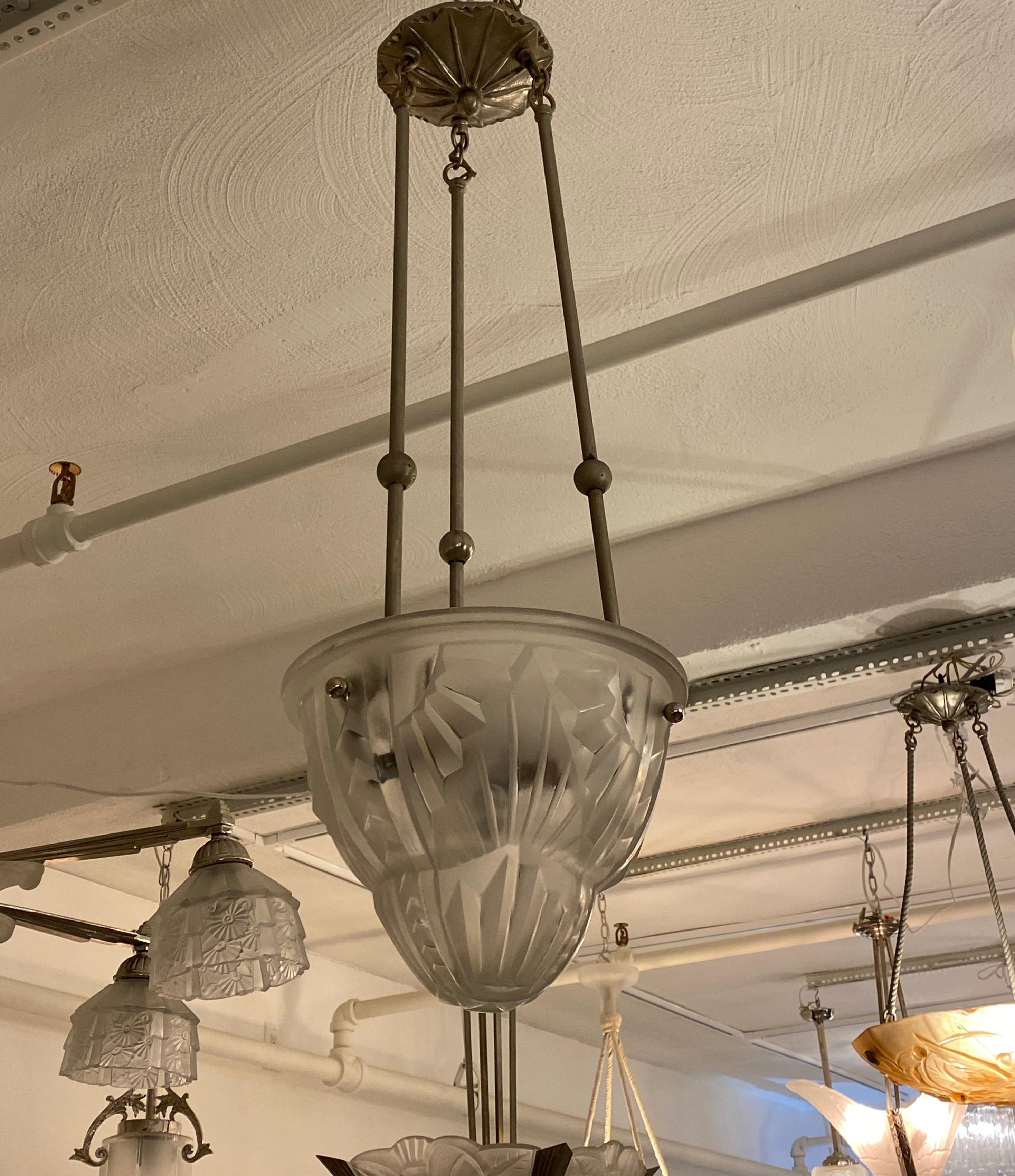 Französischer Art-Déco-Hängeleuchter des französischen Künstlers Degue. Schirm aus klarem Milchglas mit geometrischem Motiv. Gehalten von drei Nickelstäben und einer Deckenplatte. Wurde für den amerikanischen Gebrauch mit drei Kandelaberfassungen