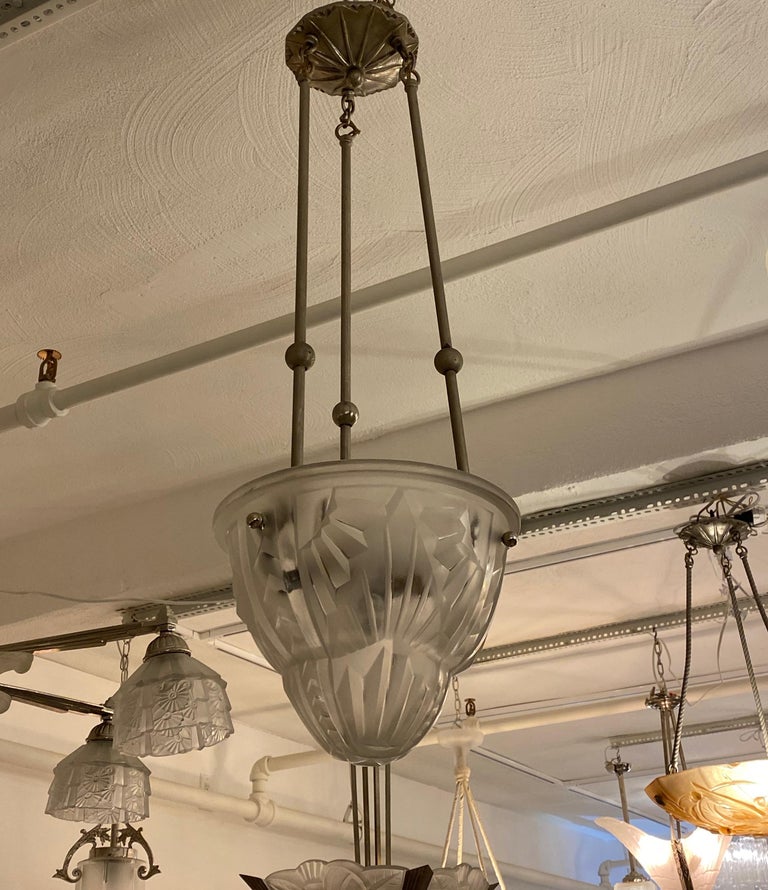 French Art Deco pendant chandelier by the French artist Degue. Clear frosted glass shade with geometric motif. Held by three nickel rods and ceiling plate. Has been rewired for American use with three candelabra sockets. Each socket has a max of 60