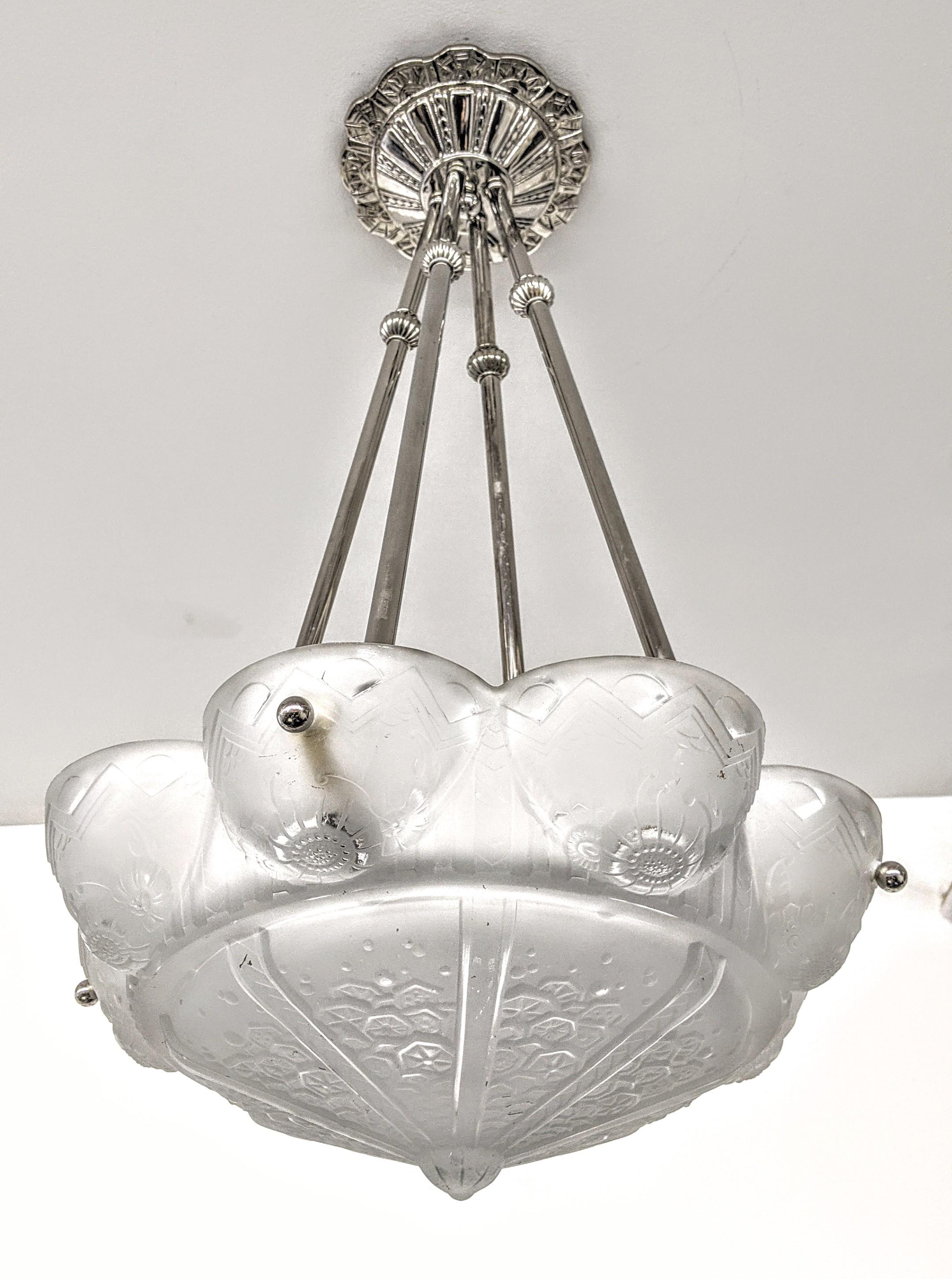 A French Art Deco pendant chandelier by the French artist-signed, marked “Muller Freres Luneville“. Clear frosted molded glass shades decorated with intricate geometric flowers polished motif details held by four rods with a dash of decorative balls