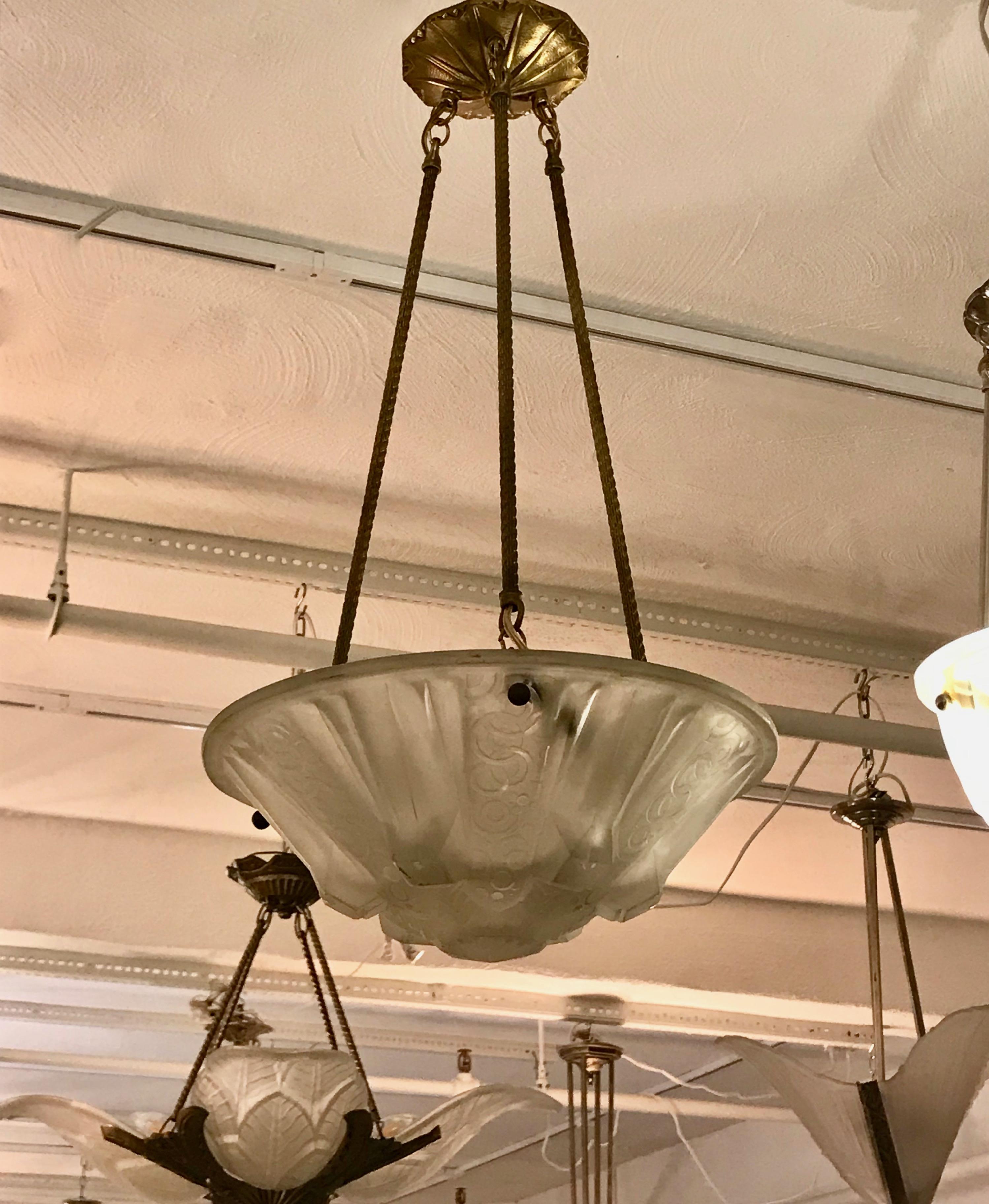 French Art Deco geometric chandelier signed by Muller Frères Luneville. Having a glass shade with geometric motif. Held by three brass rods and a matching canopy. Has been rewired for American use. Having three candelabra sockets. Each with a max