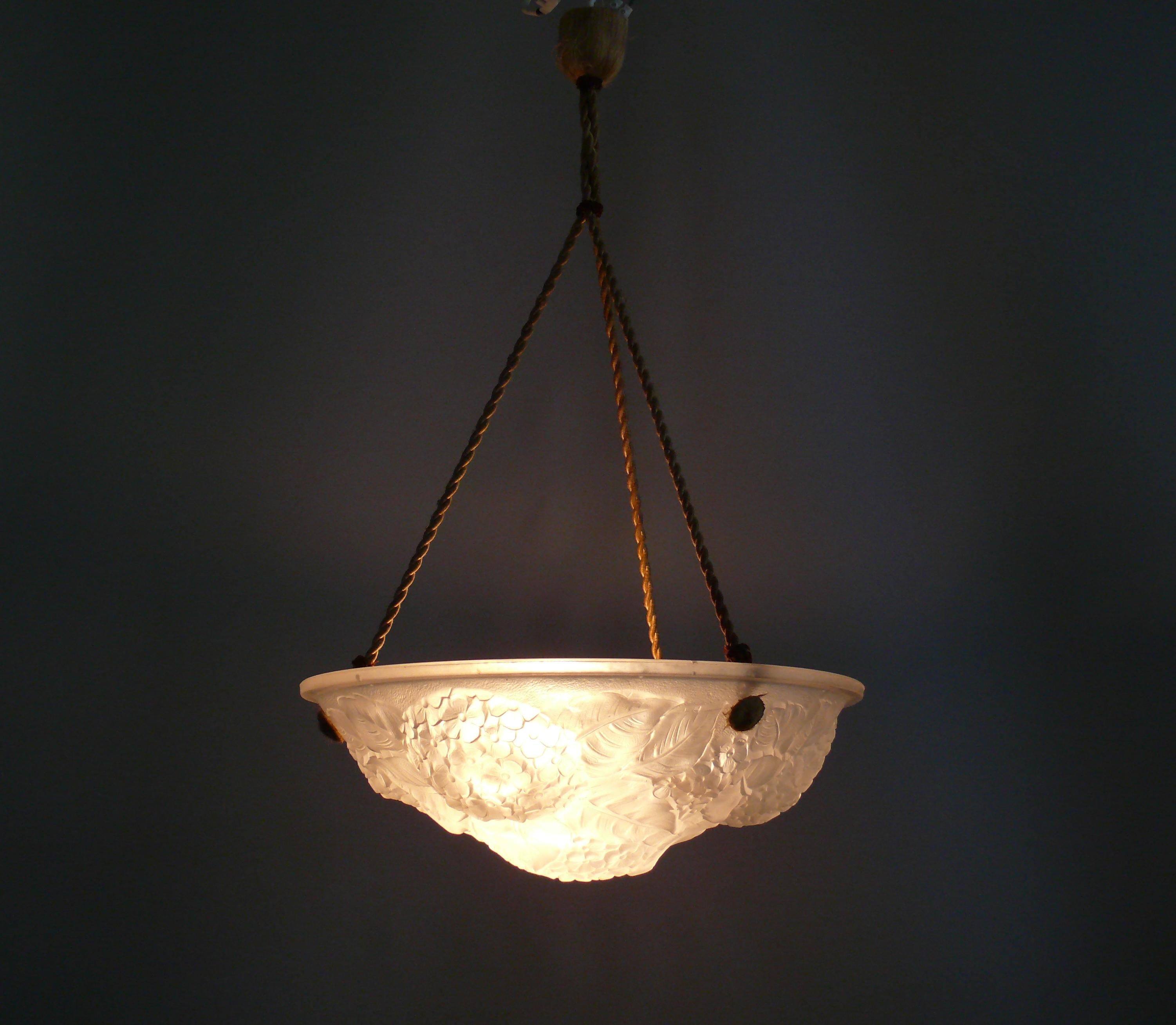 French pendant lamp from the 1920s - 1940s with an opal glass shade and cable suspension in good original condition - style: Degue, Muller Freres. The ornate glass shade has a beautiful floral texture. The suspension, socket, and cable are likely