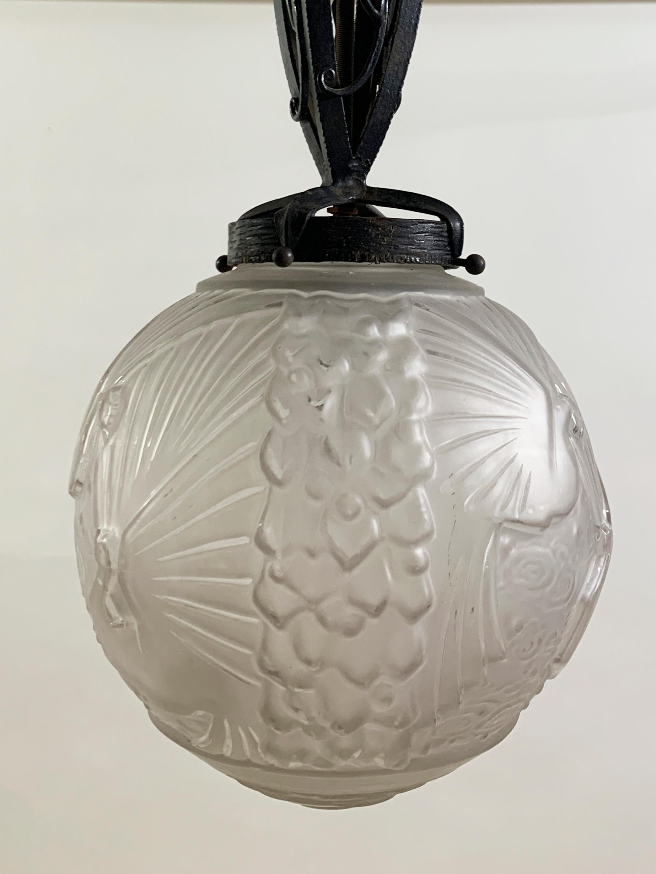 This elegant Art Deco pendant by Muller Frères Luneville exemplifies French lighting design from the 1920s–1930s. The frosted glass globe features intricate relief work depicting peacocks and stylized foliage, showcasing the exceptional