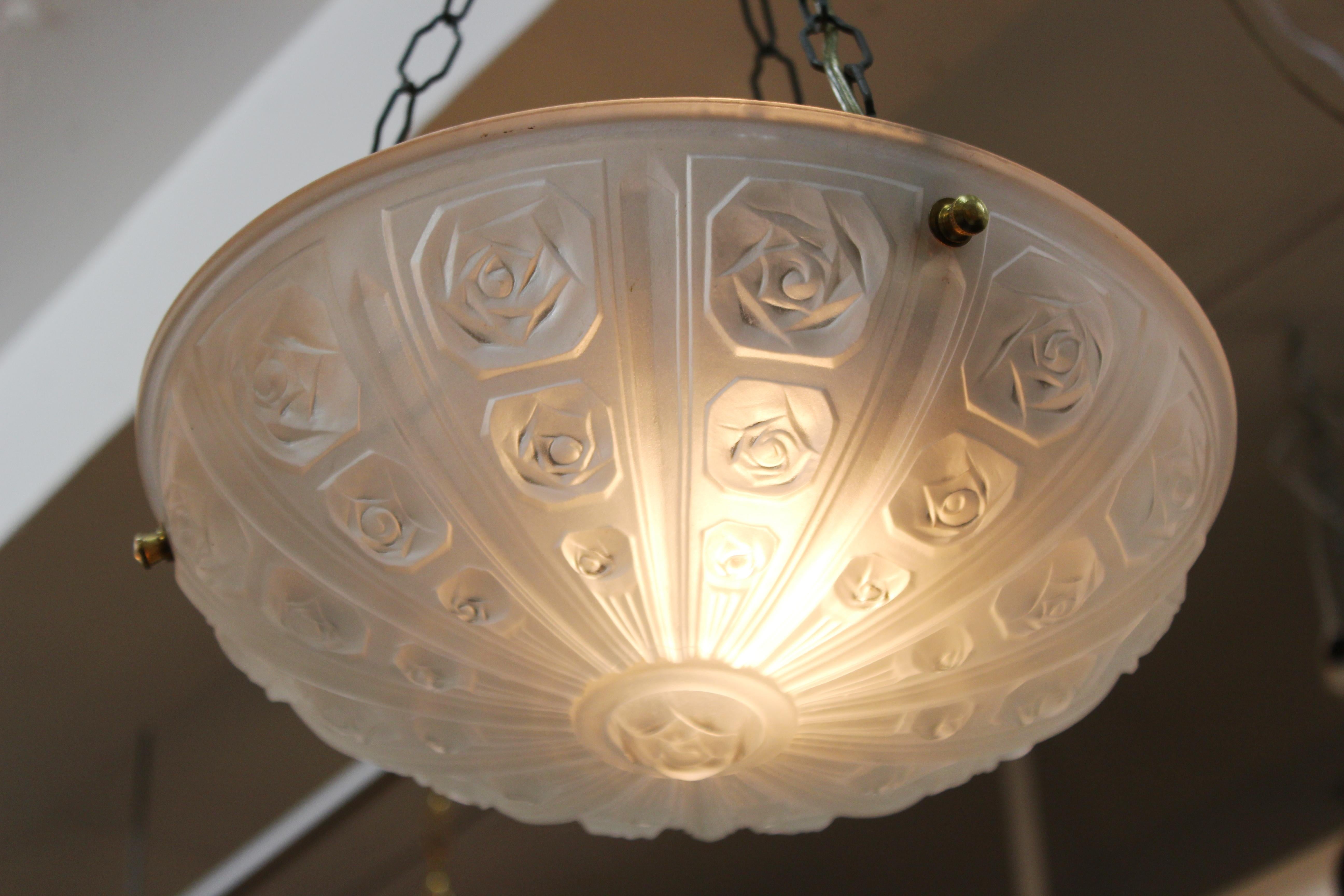 French Art Deco ceiling pendant light with a floral themed relief frosted glass bowl attached to three brass chains and a canopy piece. The piece has been newly rewired and the glass bowl itself has never been used before. Made in France during the