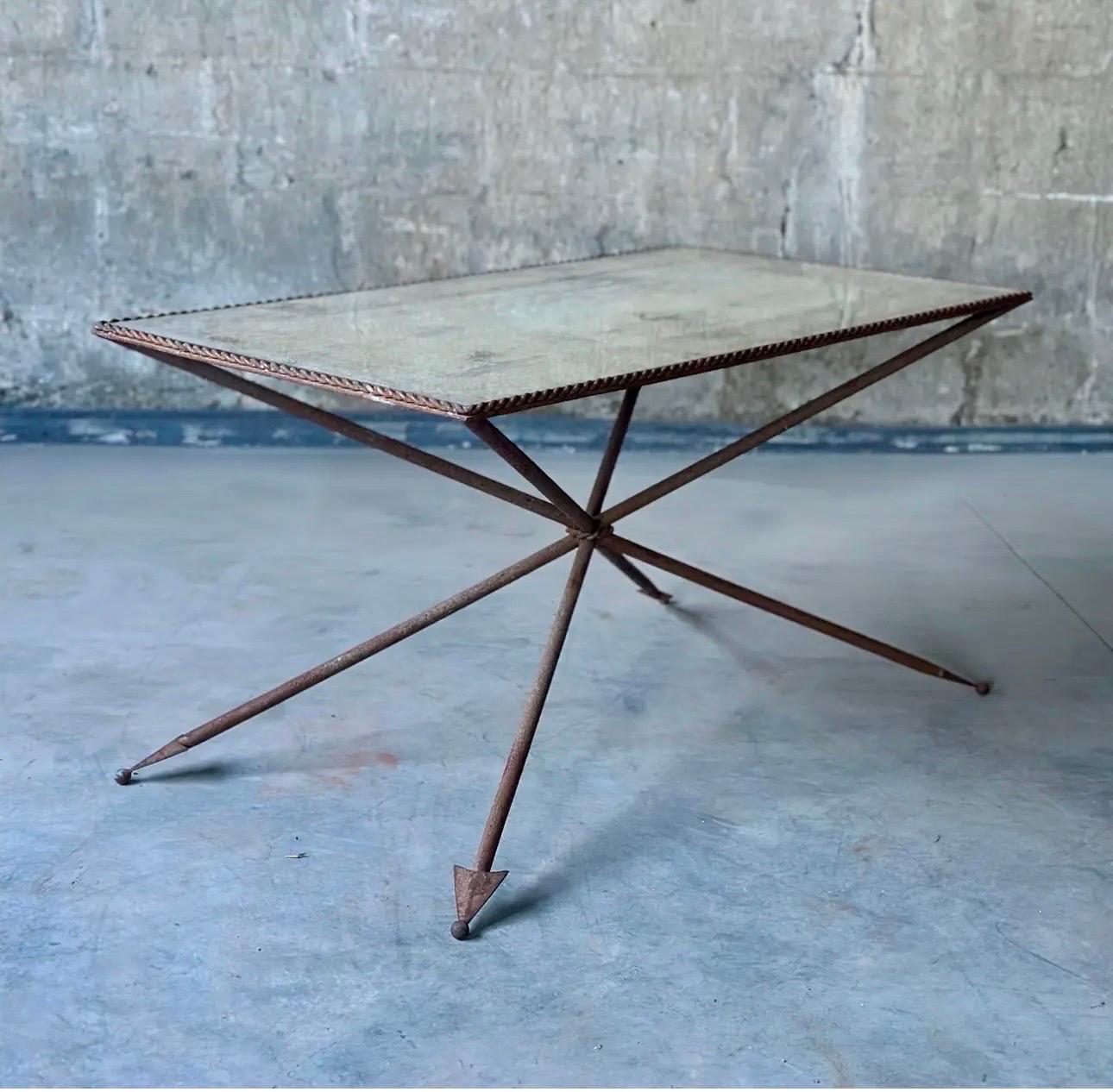 A French Art Deco period Arrow coffee table. Perfect patina on the metal table under glass, framed with a rope twist edge. Striking cross legs are finished with ball tipped arrows.