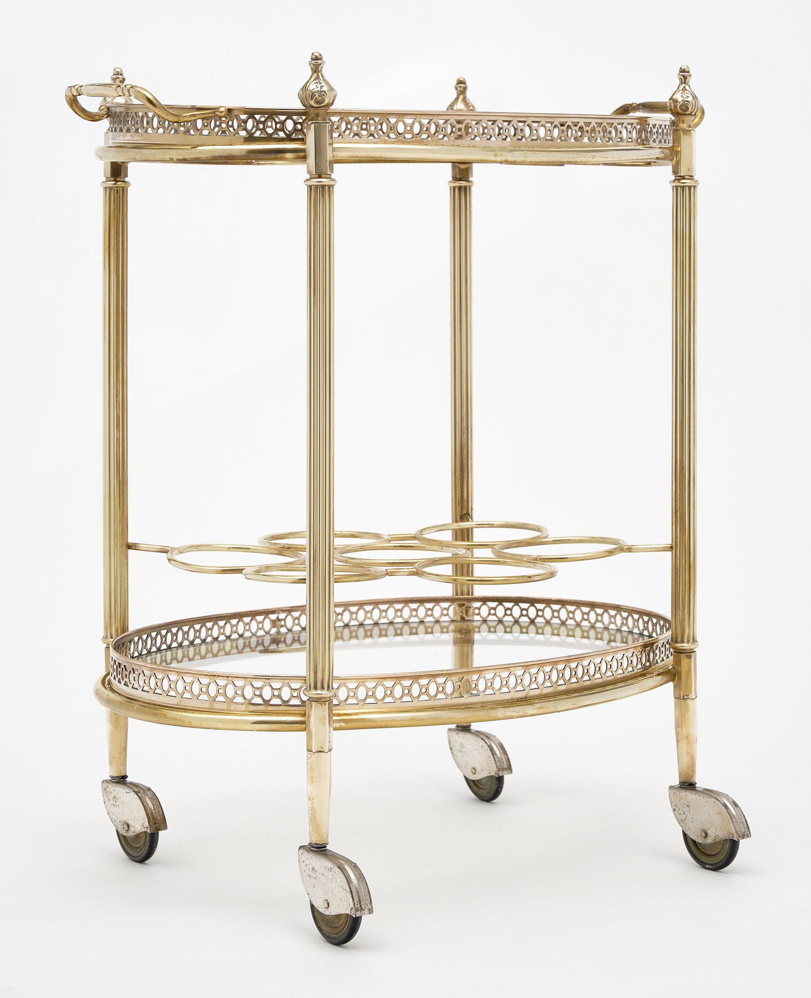 French Art Deco period bar cart made of gilt brass with two glass shelves. The top surface is a detachable tray; and the bottom features a bottle holder. The legs supporting the piece are ridged and on casters.