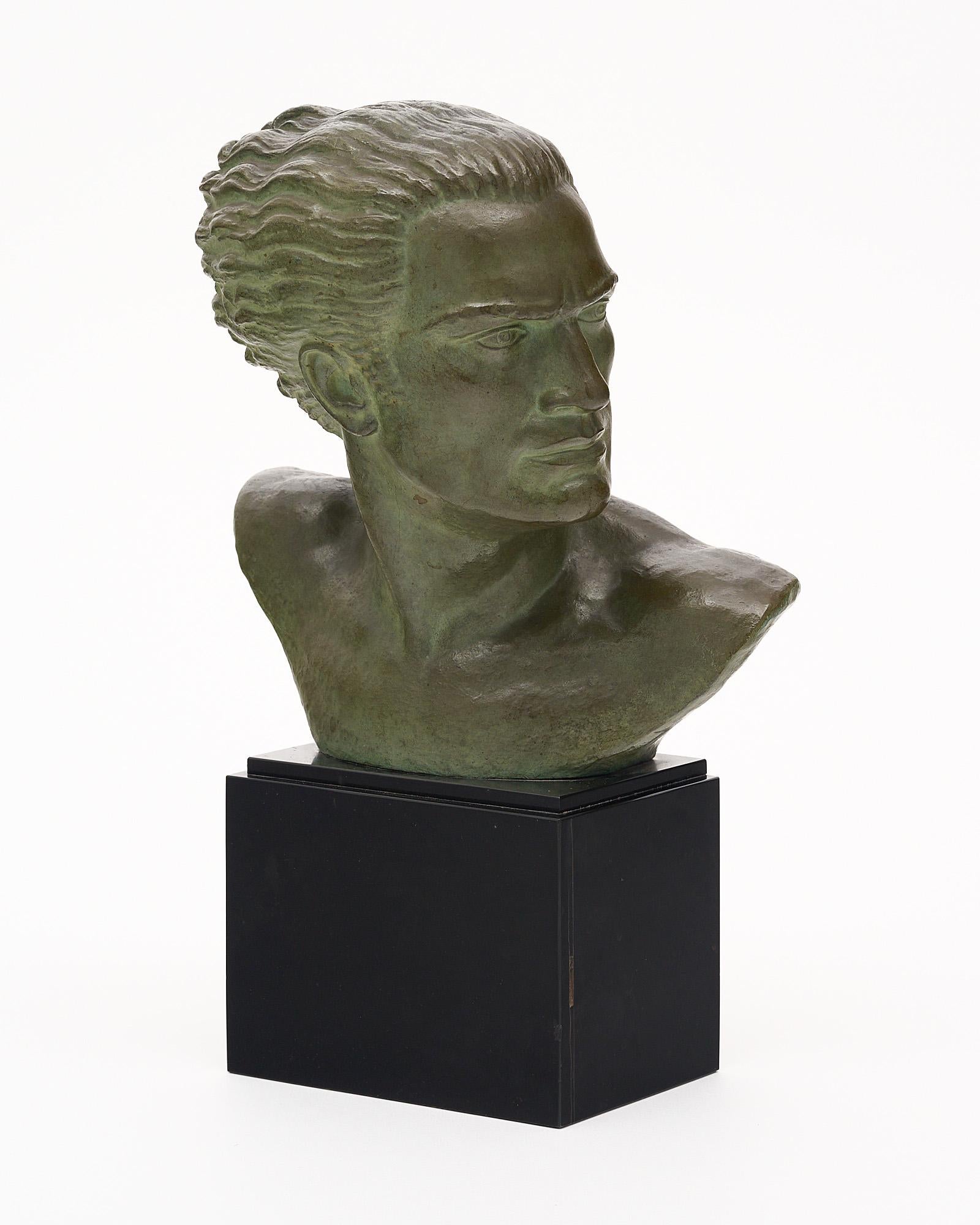 French Art Deco bronze bust of Jean Mermoz. This piece has a beautiful green patina and black marble base. Jean Mermoz was a French pioneer aviator; 1901-1936. This depicts his courageous expression with a slight movement in the hair. He was most