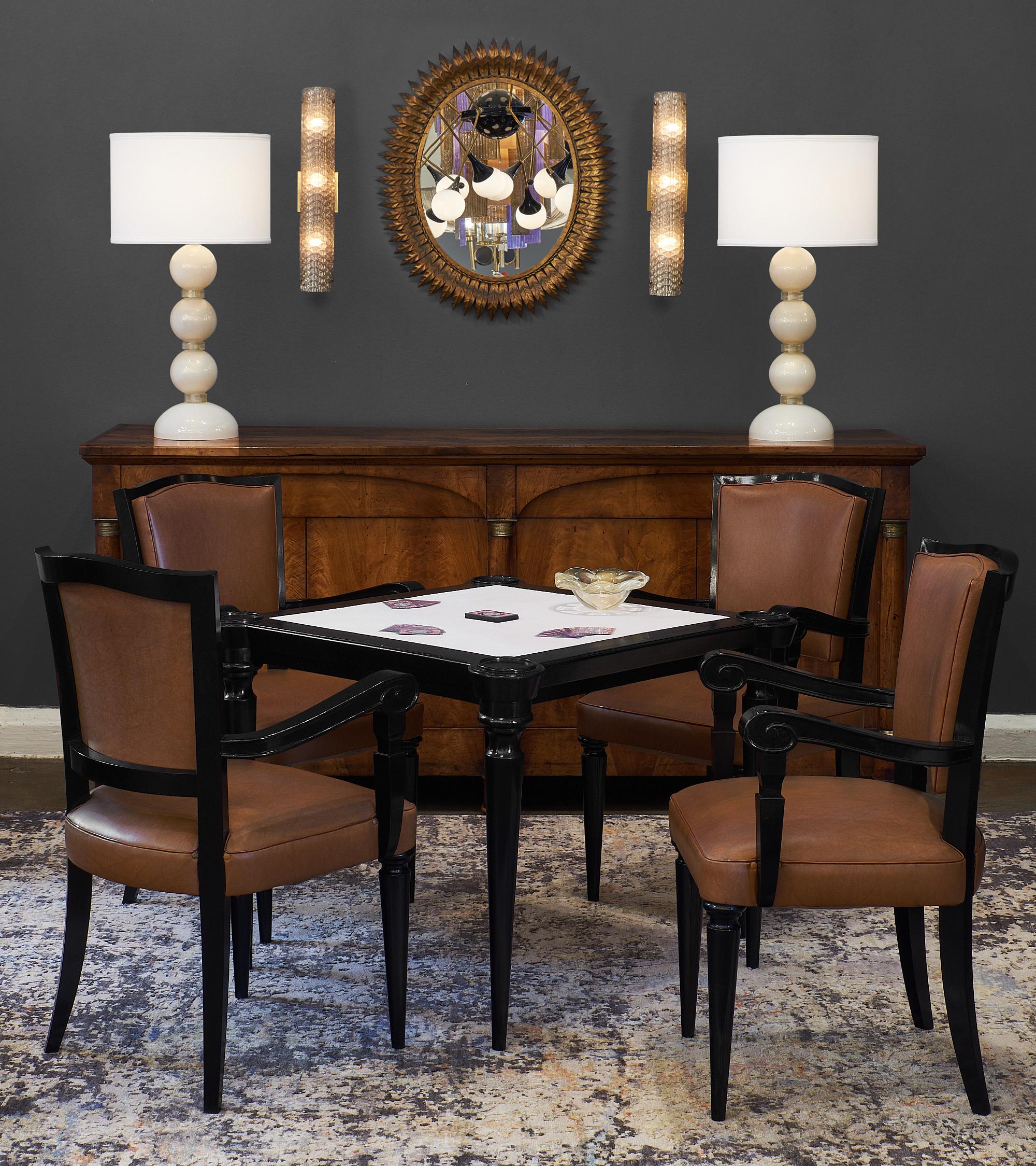 Art Deco period French game chairs made of ebonized walnut finished with a lustrous French polish. The chairs are upholstered with the original brown vinyl, in excellent vintage condition. We love the detail and strength of this set. The table