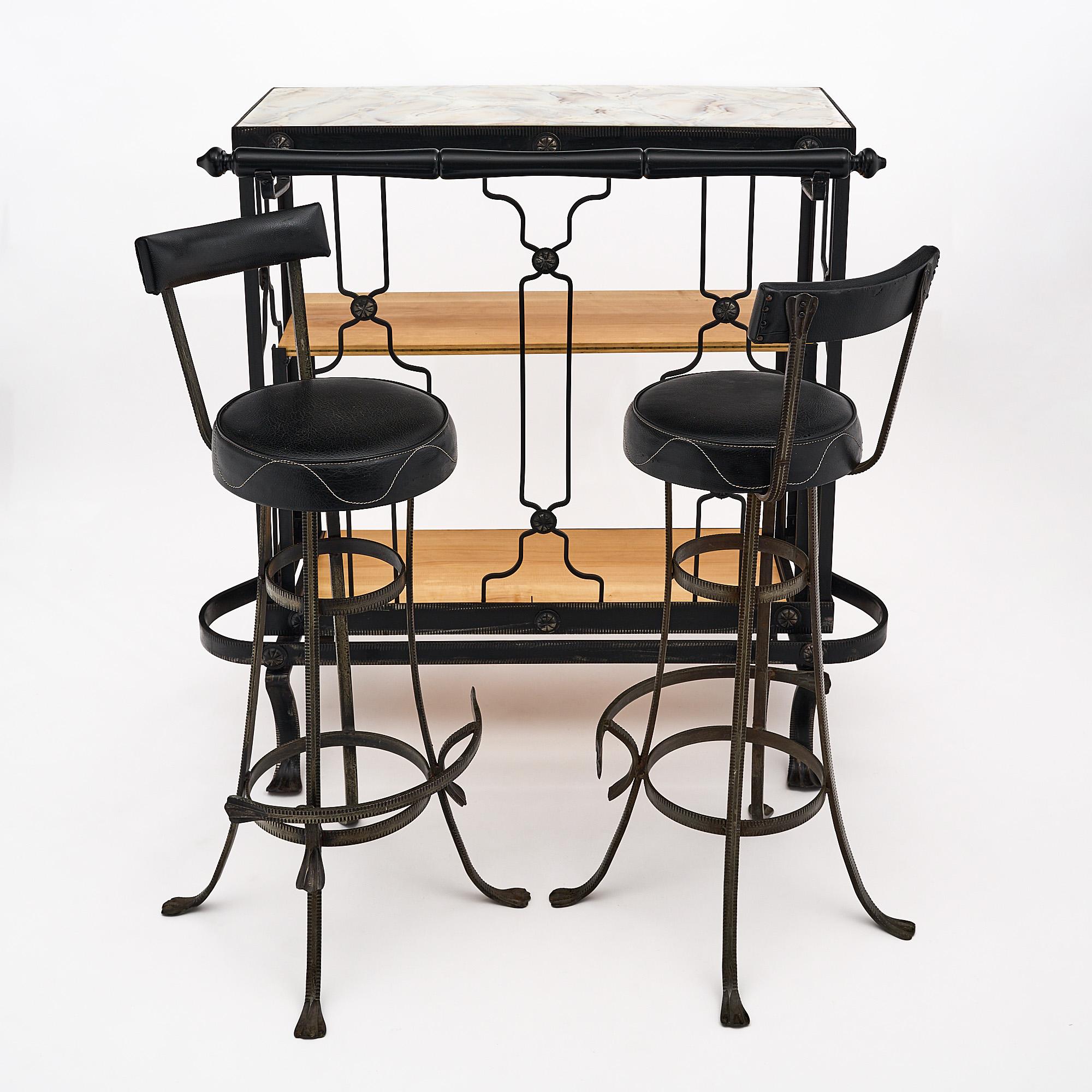 Bar and stools, French, from the Art Deco period. This set is made of hand-hammered forged iron with a custom glass top. The original vinyl upholstery is on the stools and there are two interior wood shelves. The dimensions listed are for the bar,