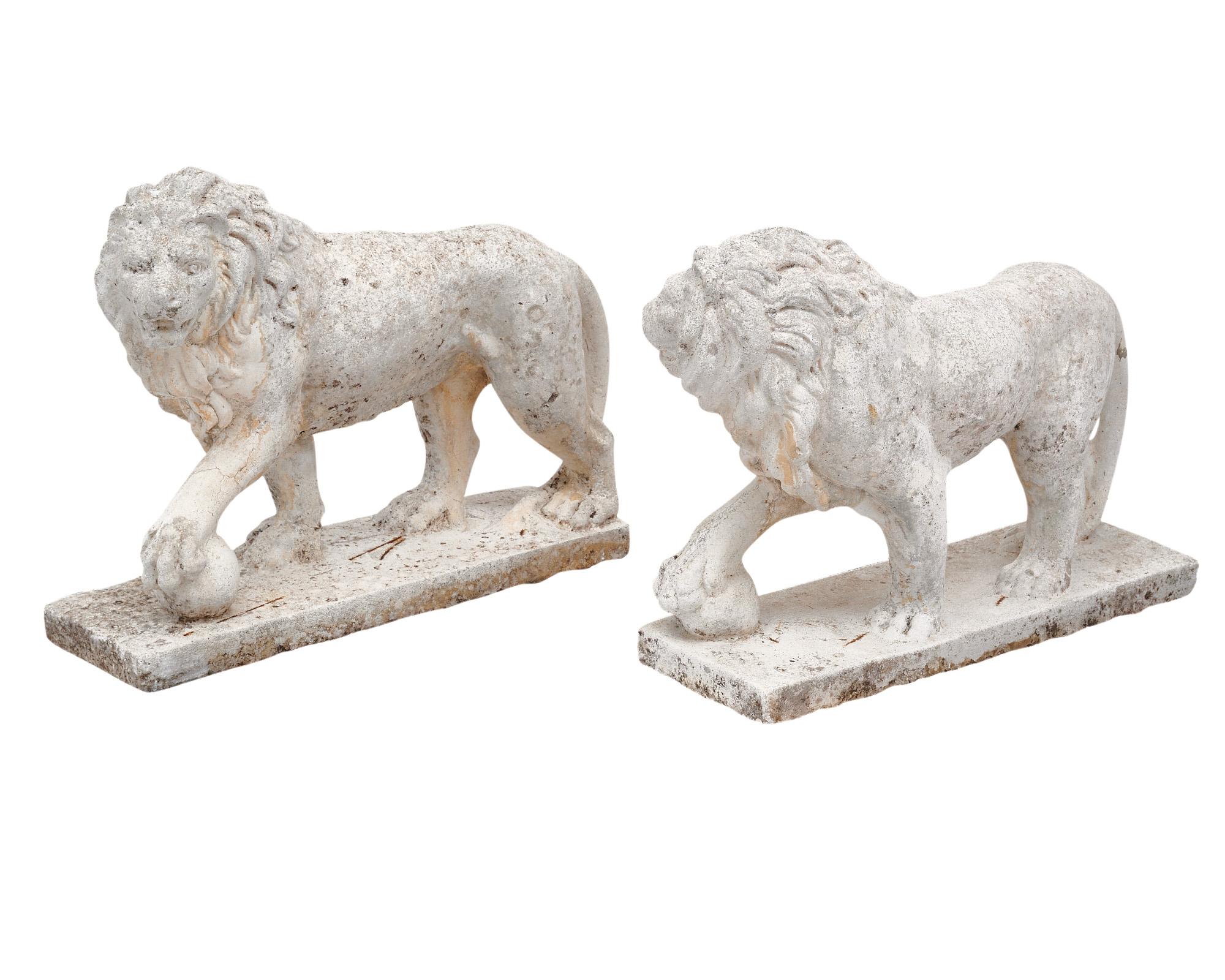 Pair of sculptures from the Art Deco period in France. Each is sculpted into the shape of a lion, featuring one outstretched paw on a ball and supported by a base. These sculptures are made of reconstituted stone. Reconstituted stone; also known as