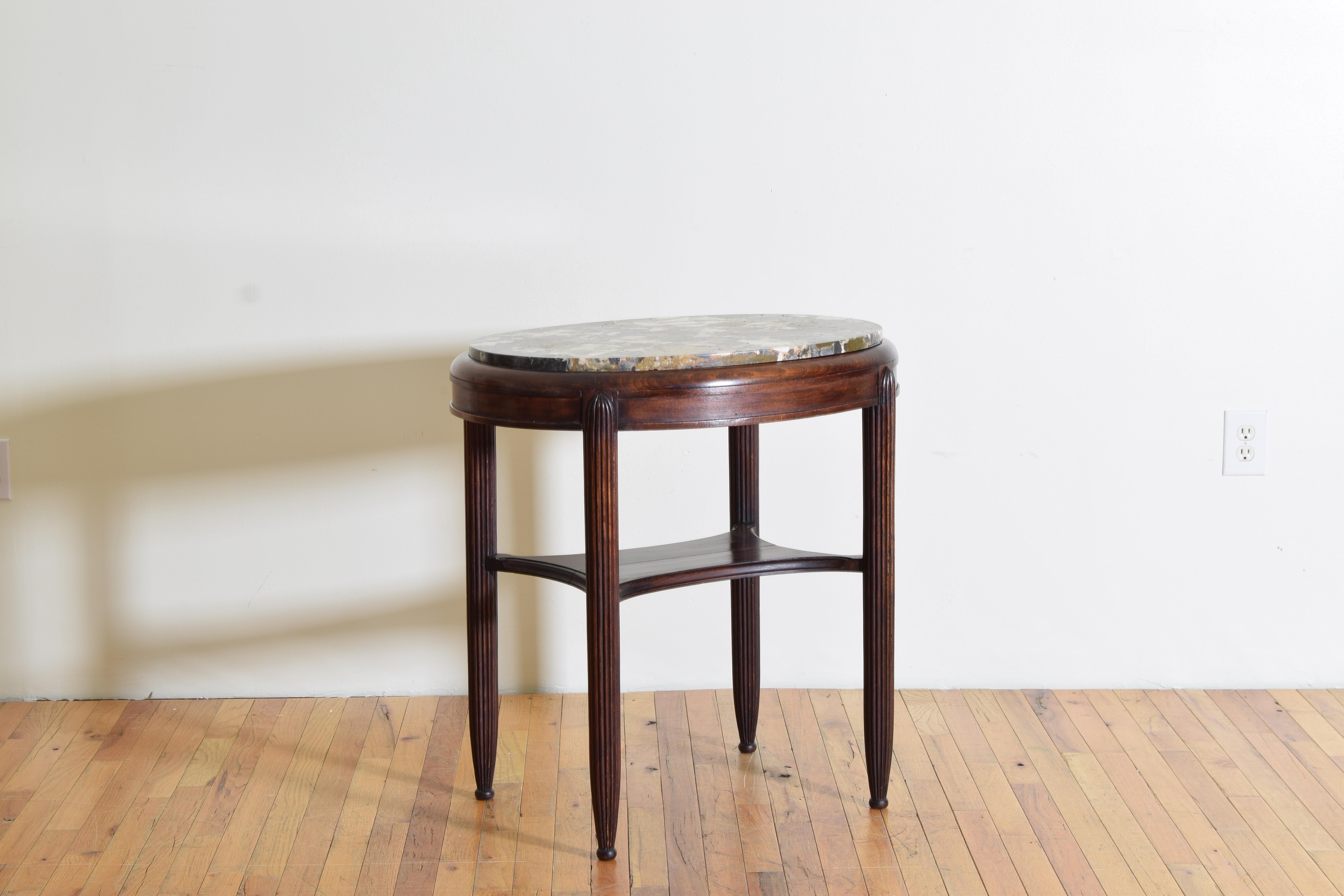 A castle-scaled side table with a conglomerate marble top and reeded legs.