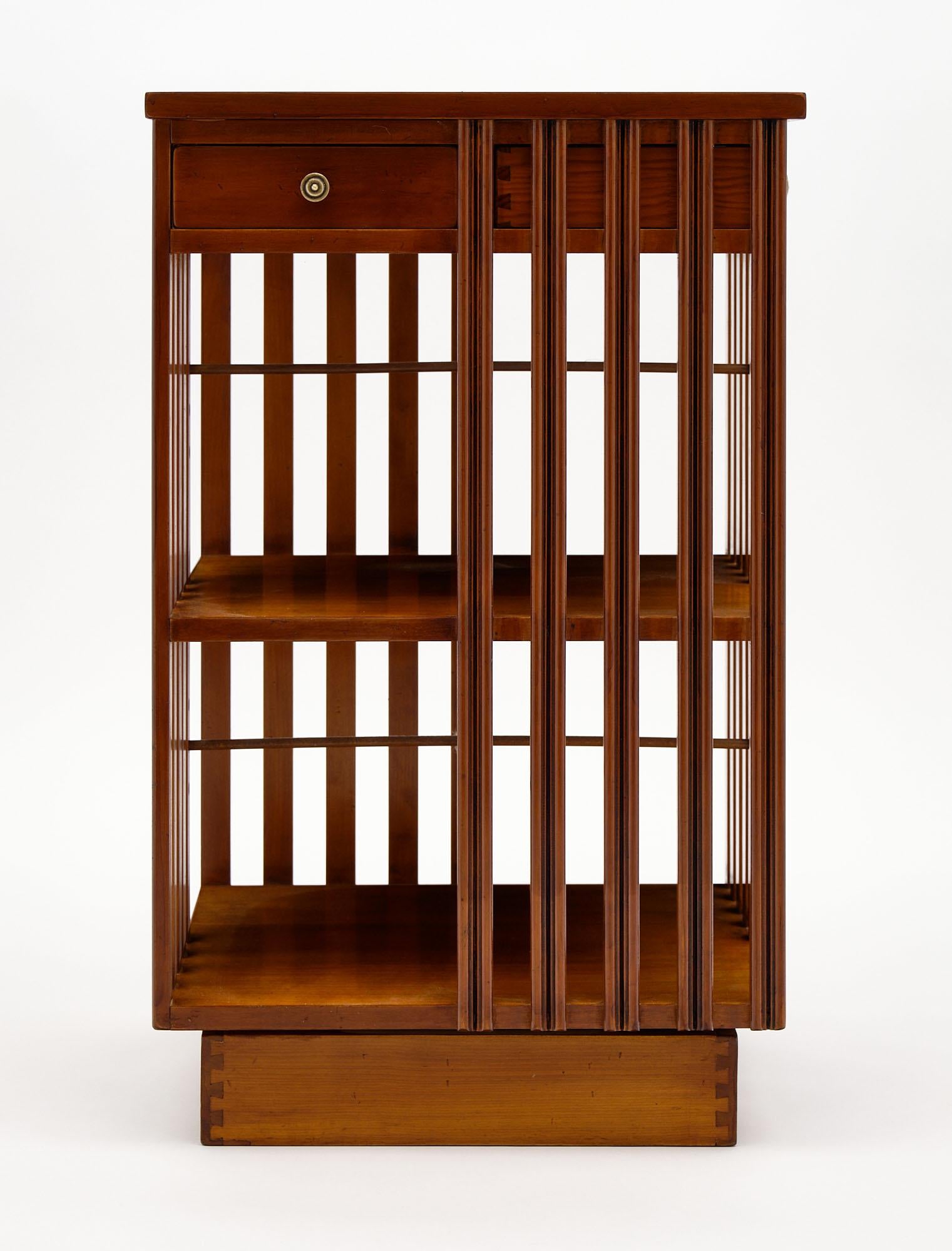 French Art Deco period revolving bookcase or side table made of solid walnut with two drawers. We love the revolving design and the beautiful warmth of the wood. It can be used as a side table as well!
