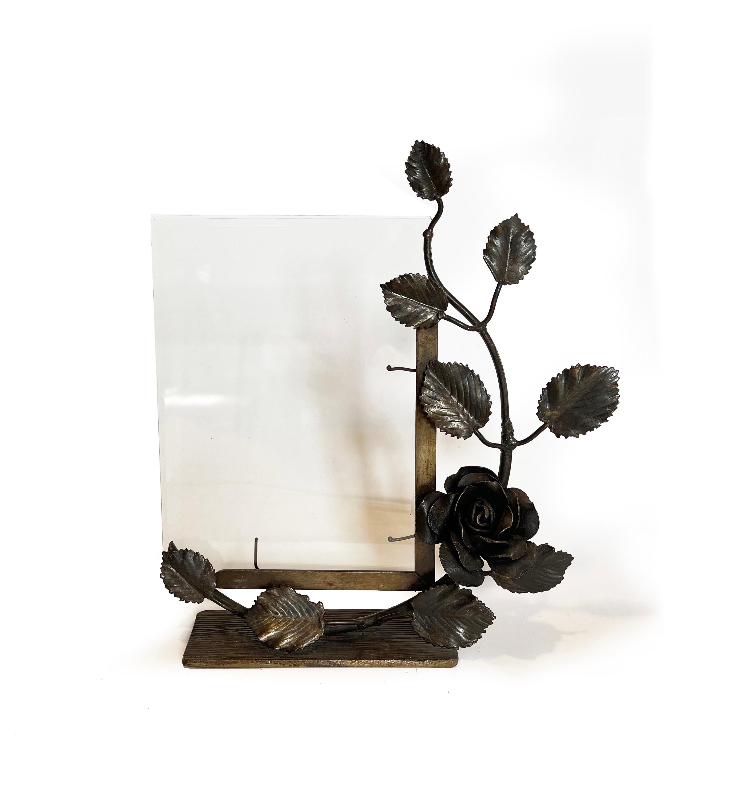 Beautifully forged picture frame of the art deco period.
Delicately shaped rose vine arranged around the rectangle picture frame, which holds the beveled glass.
The glass is held by tentacle-like arms, and measures 9'' (233 mm) x 6.7'' (171 mm)