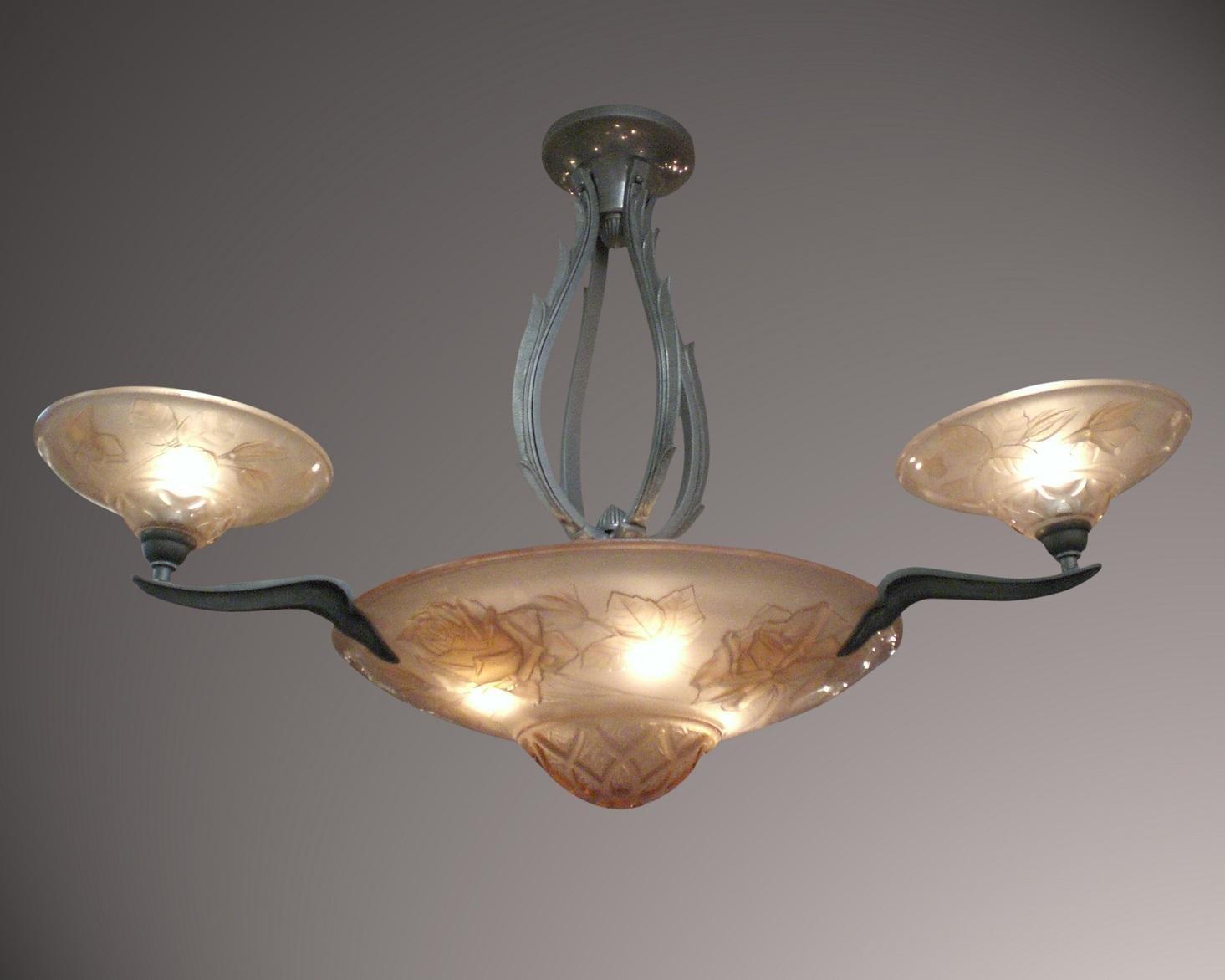 An original colorful French Art Deco living coral tinted, heavily molded art glass chandelier depicting realistic rose and leaf pattern
Signed : Verdun
 Three satellite dishes surround a central coupe while suspended by a flame-like or vine-like