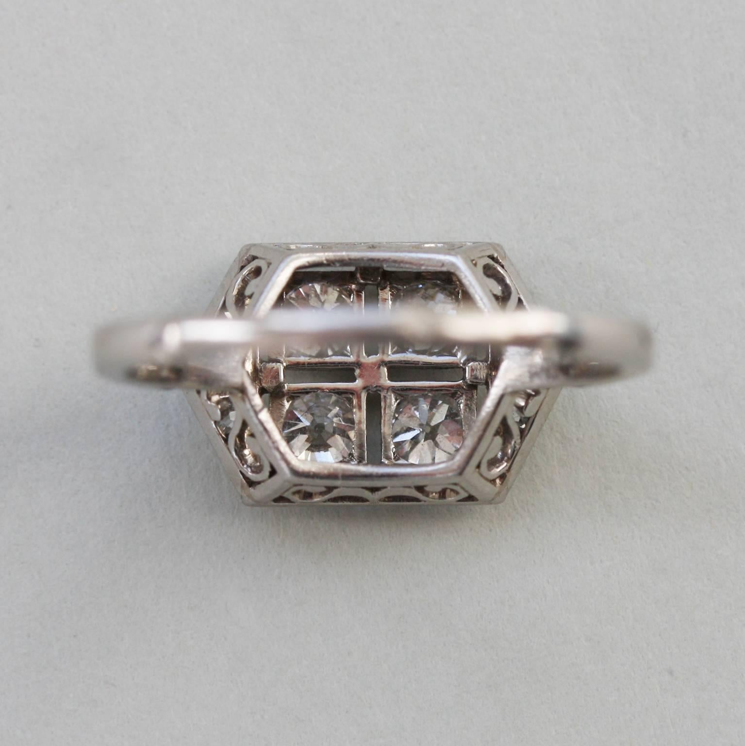 A platinum ring set with four old-cut diamonds in a square. Each stone is mille-griffe set; and on either side of the square is a little triangle set with three old-cut diamonds (total diamond weight app. 0.7).  The shank is numbered: 27500; and