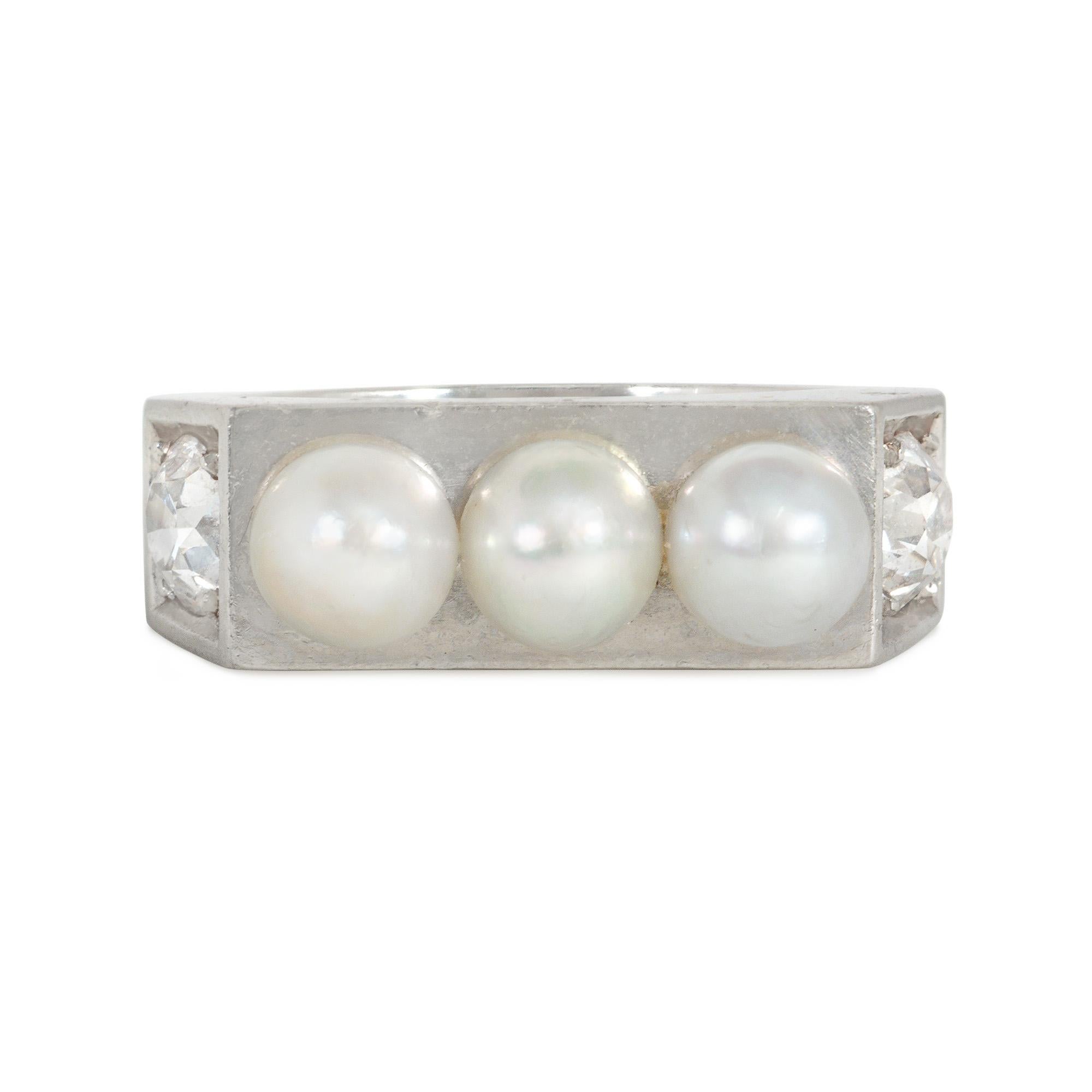 An Art Deco pearl and diamond band-style ring of geometric design, centered by a horizontal row of three natural pearls, with canted shoulders featuring in-set diamonds, in platinum. French assay marks.  Atw diamonds 1.00 ct.

Face-up dimensions: