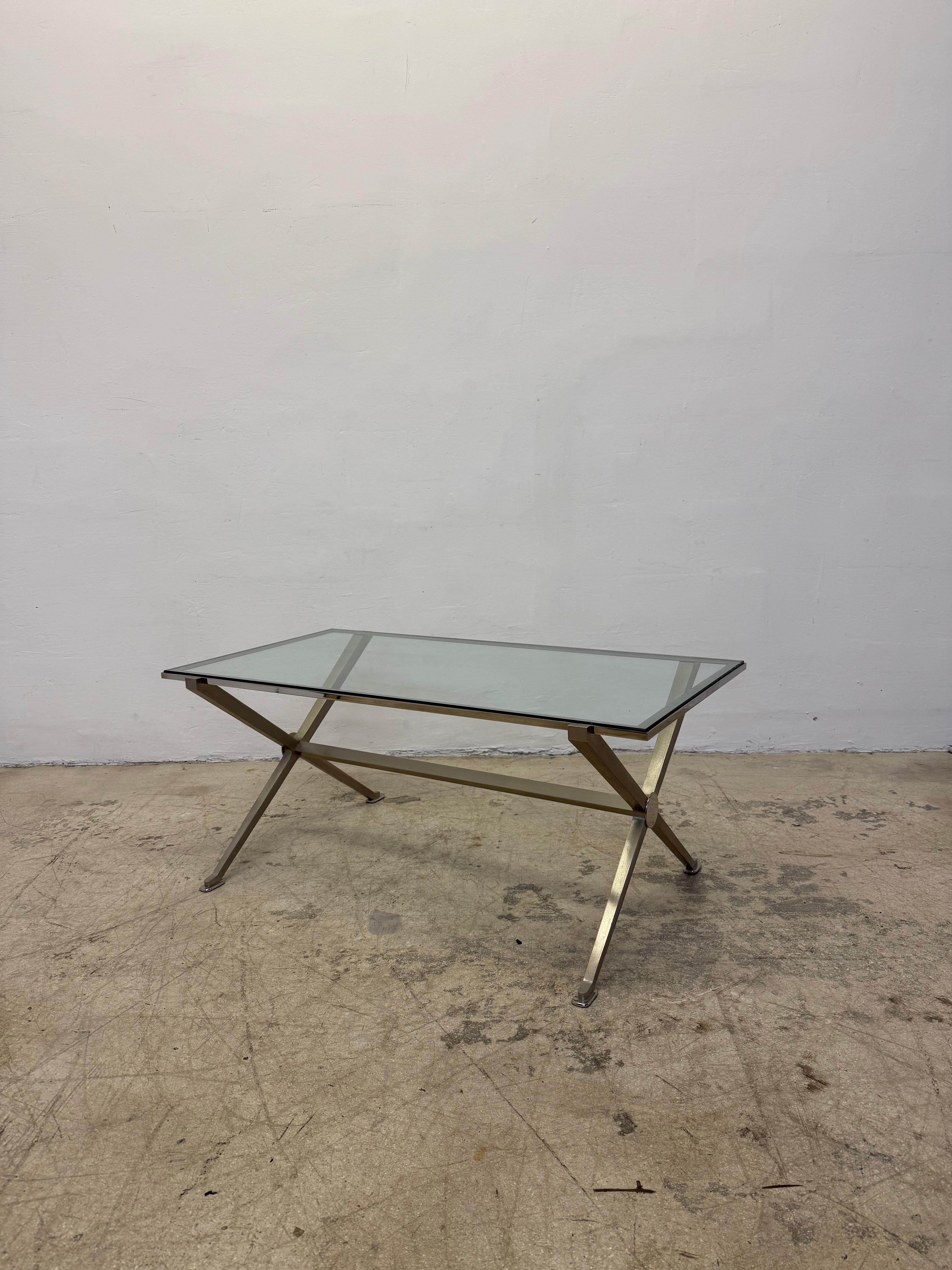 Inset glass top coffee or cocktail table with brushed steel frame and chrome accents circa 1970s.  This French Art Deco inspired table most closely resembles designs by Maison Jansen, Jean Maurice Rothschild and John Vessey.

Table 1 of 2.  Please