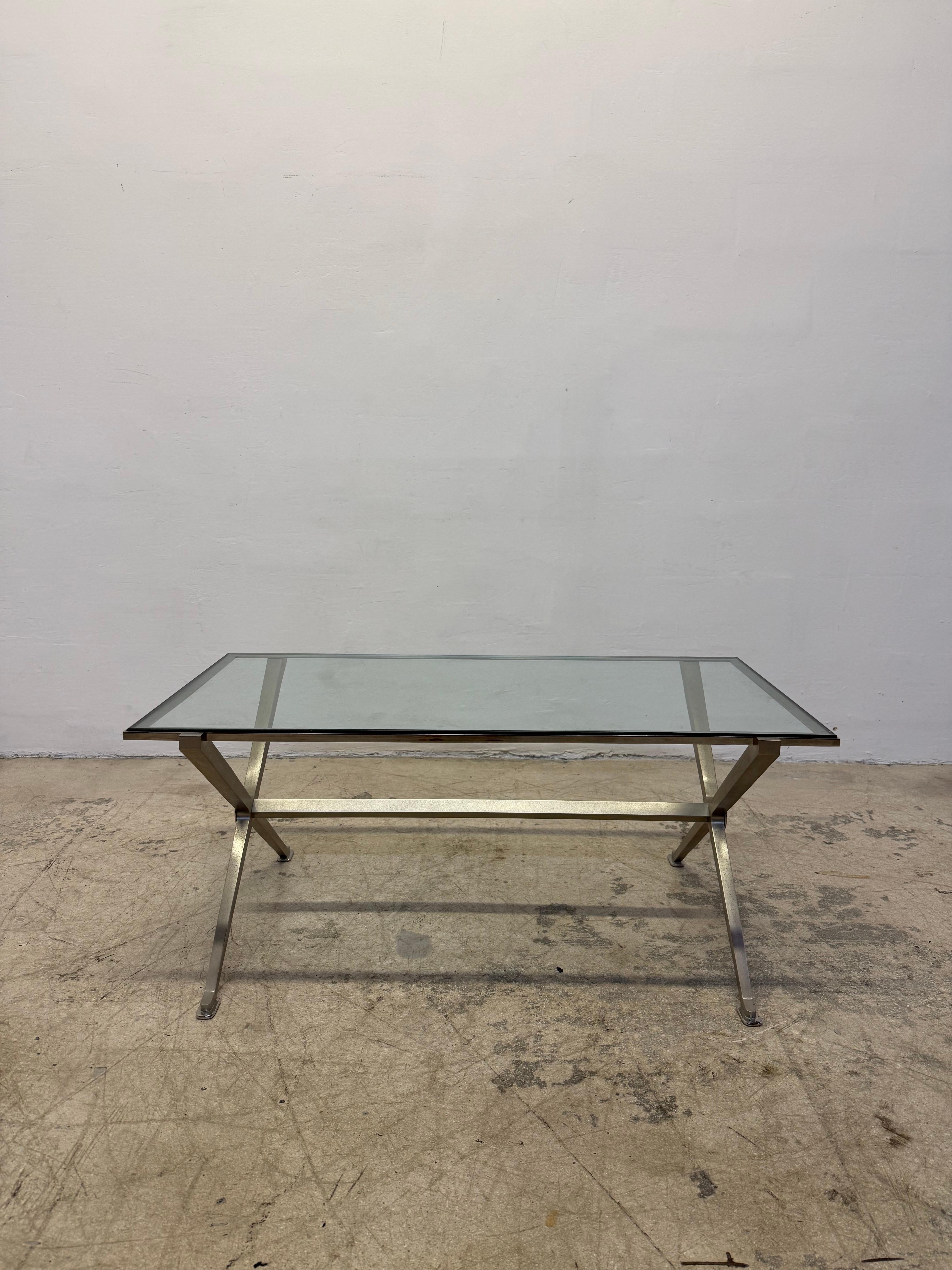 Inset glass top coffee or cocktail table with brushed steel frame and chrome accents circa 1970s.  This French Art Deco inspired table most closely resembles designs by Maison Jansen, Jean Maurice Rothschild and John Vessey.

Table 2 of 2.  Please