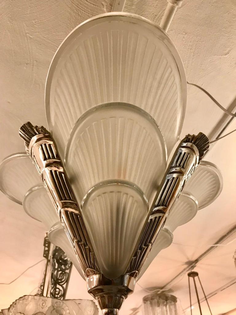 French Art Deco chandelier. Having three clear frosted glass panels having ribbed motif with polished details. Held by a matching polish nickel bronze frame with a geometric design. Has been rewired for American use with three candelabra sockets.