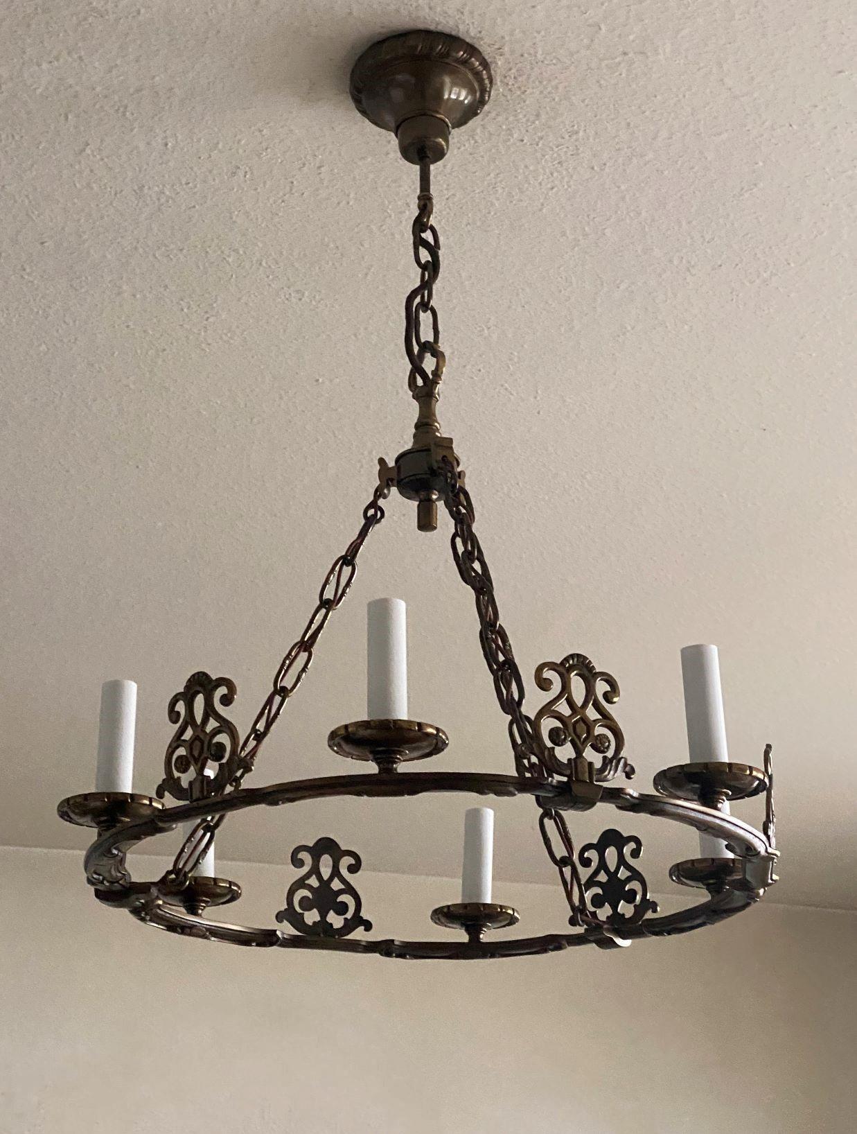 A very elegant ring shapped chandelier of old bronze in country house style, France, 1930s. Large ring supporting six candelabra lights, suspended by three bronze chains conecting to a large ceiling canopy.
In very good condition, no damages,