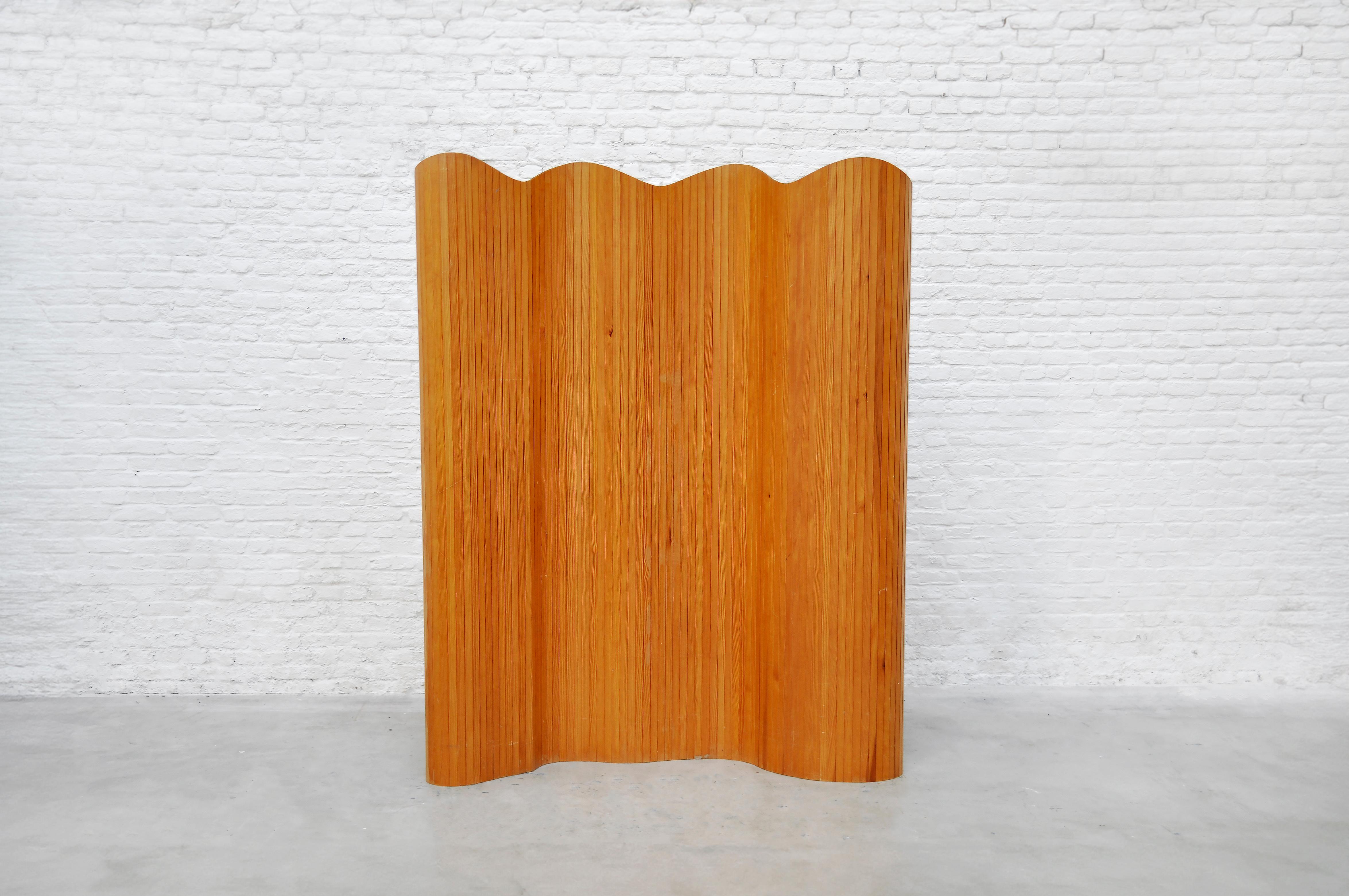 This French Art Deco freestanding room divider, dating from the 1940s, is crafted from patinated pine and remains in excellent original condition. The flexible tambour design allows the screen to be folded, coiled, or extended into various positions