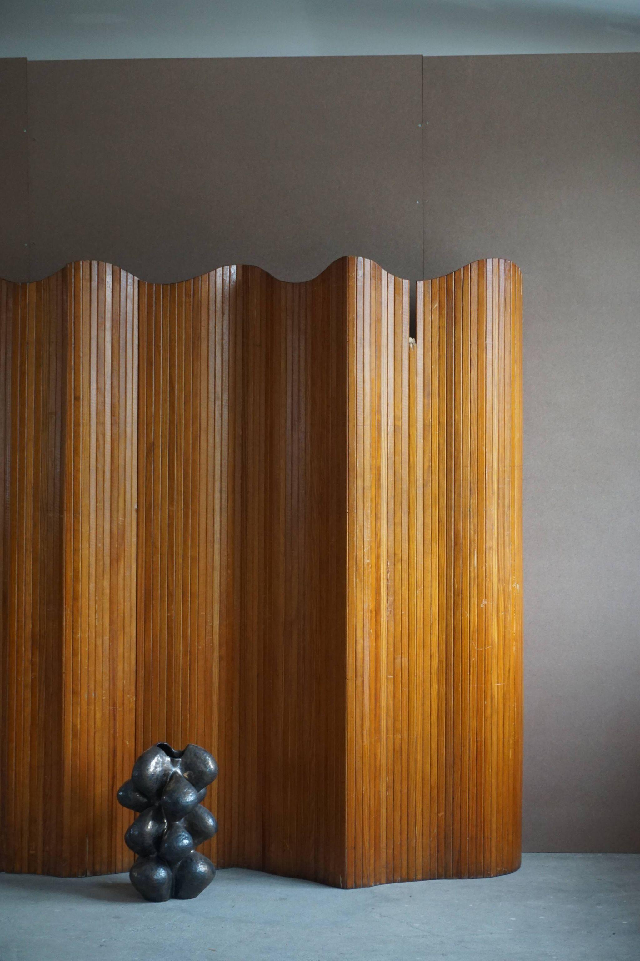 French Art Deco freestanding room divider / folding screen in patinated pine by Firm Baumann, Paris, 1940s.

Signed with applied brass manufacturer´s label.
Provience: (Paris, 8 Rue, Abel).

The screen can be folded, coiled or extended into any