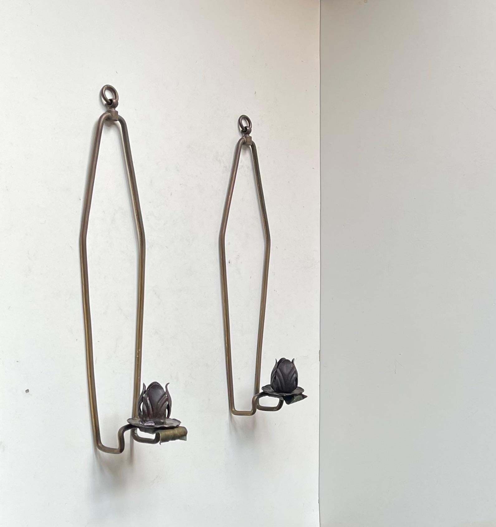A simple yet stylish configuration in the shape of these wall mounted candlesticks. Made in France circa 1920-30 in a style reminiscent of Josef Frank. They are fashioned from solid brass featuring slightly squeeze'able/adjustable rose buds
