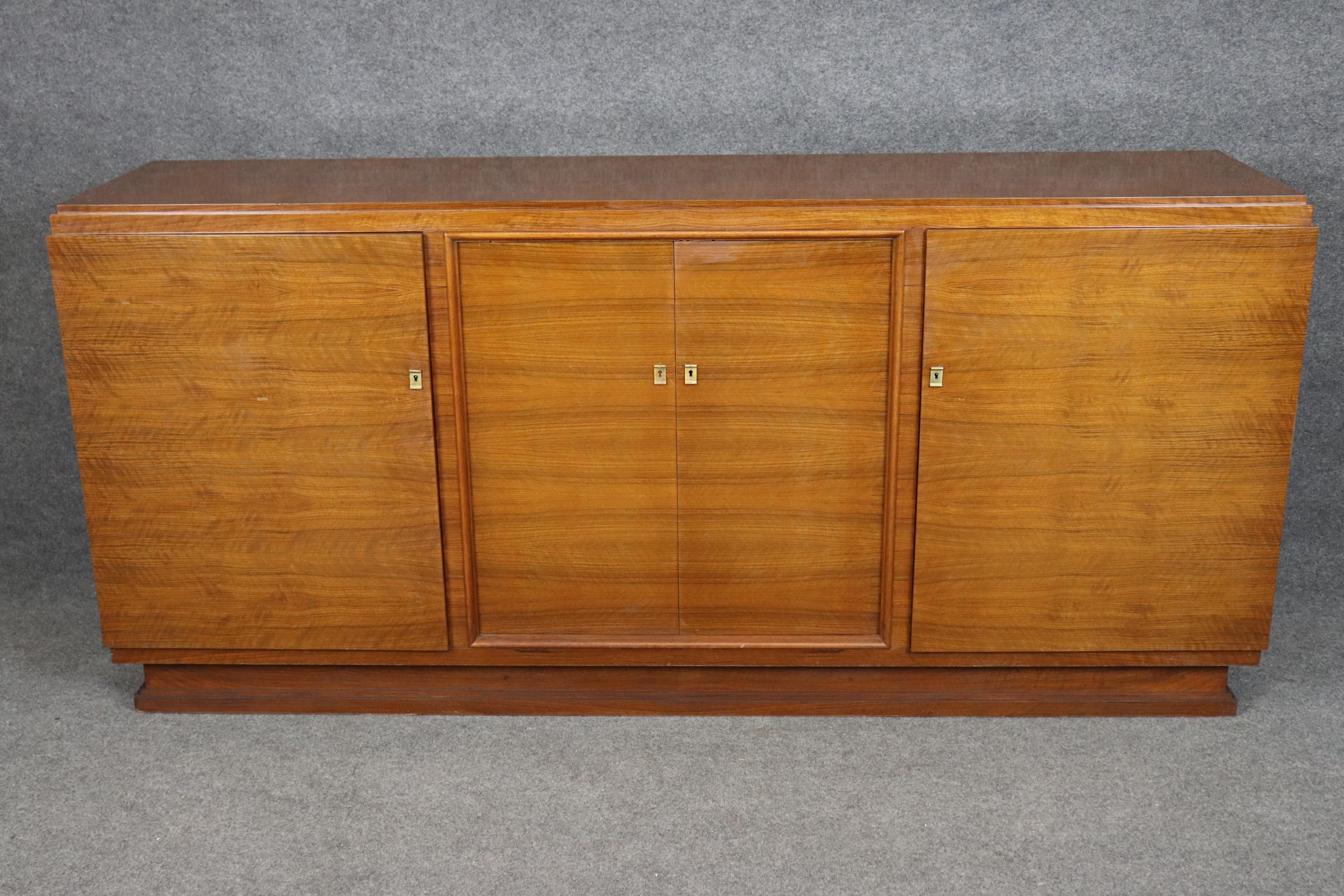Dimensions - H: 38 3/4 in W: 84 3/4 in D: 20 in 

An exceptional and finely crafted French Art Deco rosewood sideboard, designed in the manner of Émile-Jacques Ruhlmann, one of the most celebrated designers of the early 20th century. This exquisite
