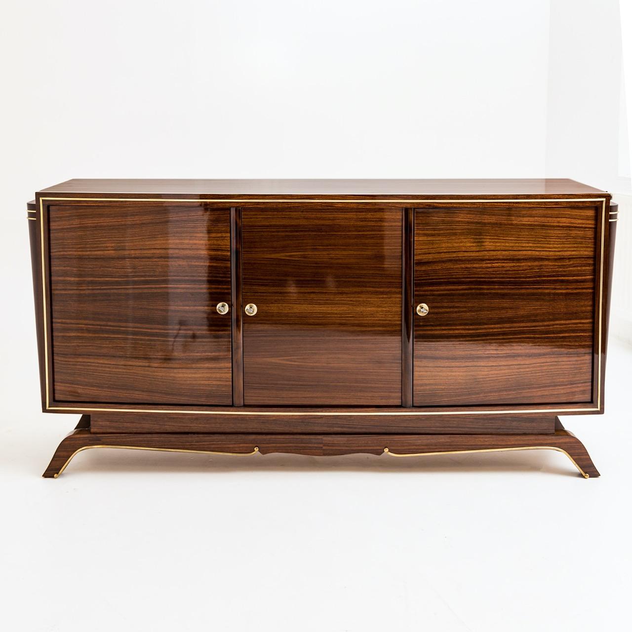 Elegant French Art Deco brass enfilade/sideboard composed of three doors in a dark rosewood veneer and adorned with applied brass trim with lemon wood interior
Date: 1930’s
Origin: France
Condition: Excellent repolished condition
Dimensions: 37”