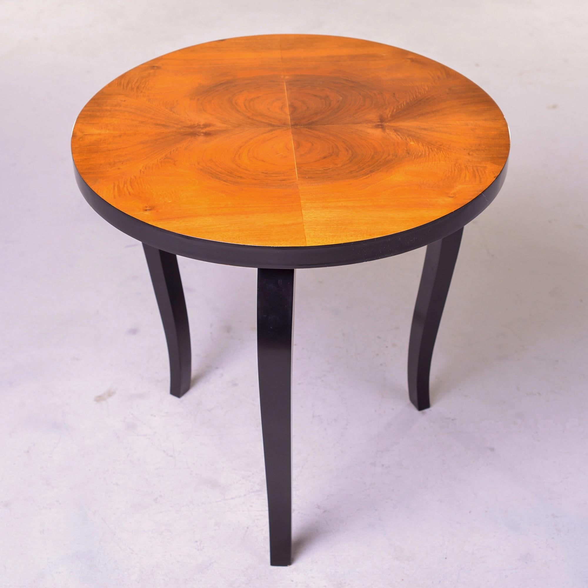 Circa 1930s round French side table in a burled walnut veneer with contrasting black stained legs and edge. Unknown maker. Very good vintage condition.