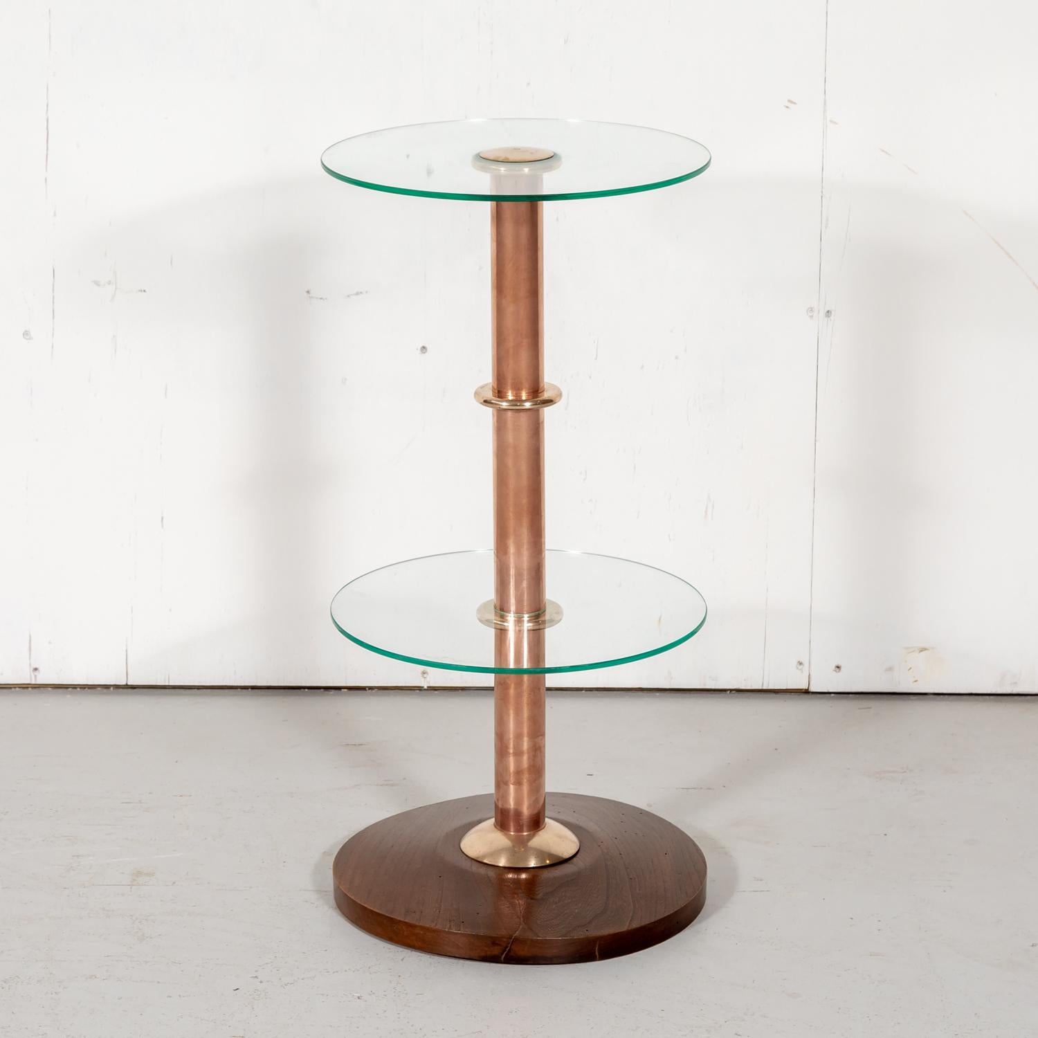French Art Deco drink occasional or side table, circa 1930s, having a solid chestnut base and copper stem with a round glass top, glass shelf, and brass accents. The perfect size for a drink or an orchid, this sleek and chic drink table adds a