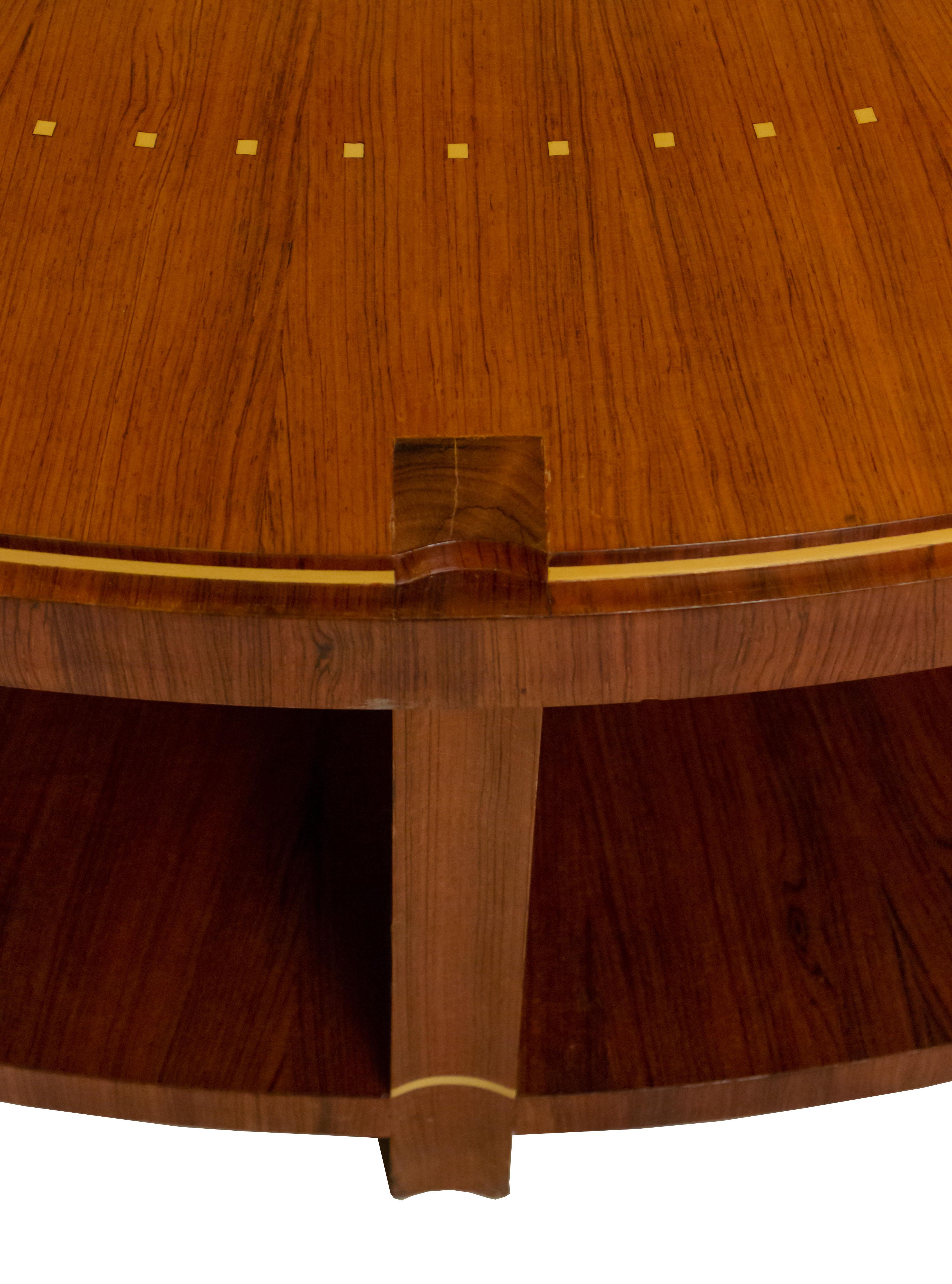 French Art Deco-style round rosewood coffee table with a radiating sunburst grain pattern inlaid with geometric designs along edge and trim supported on wooden columns connecting to a lower bottom shelf. (Manner of EMILE-JACQUES RUHLMANN).
   