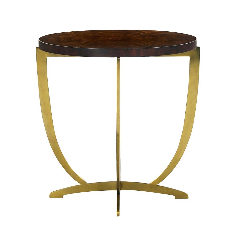 Cette table est empreinte d'une grâce sculpturale et d'une sophistication intemporelle. Son plateau rond est fabriqué en acajou crotch richement figuré, présentant un grain radial qui ajoute de la texture et du mouvement visuel. La surface lisse et