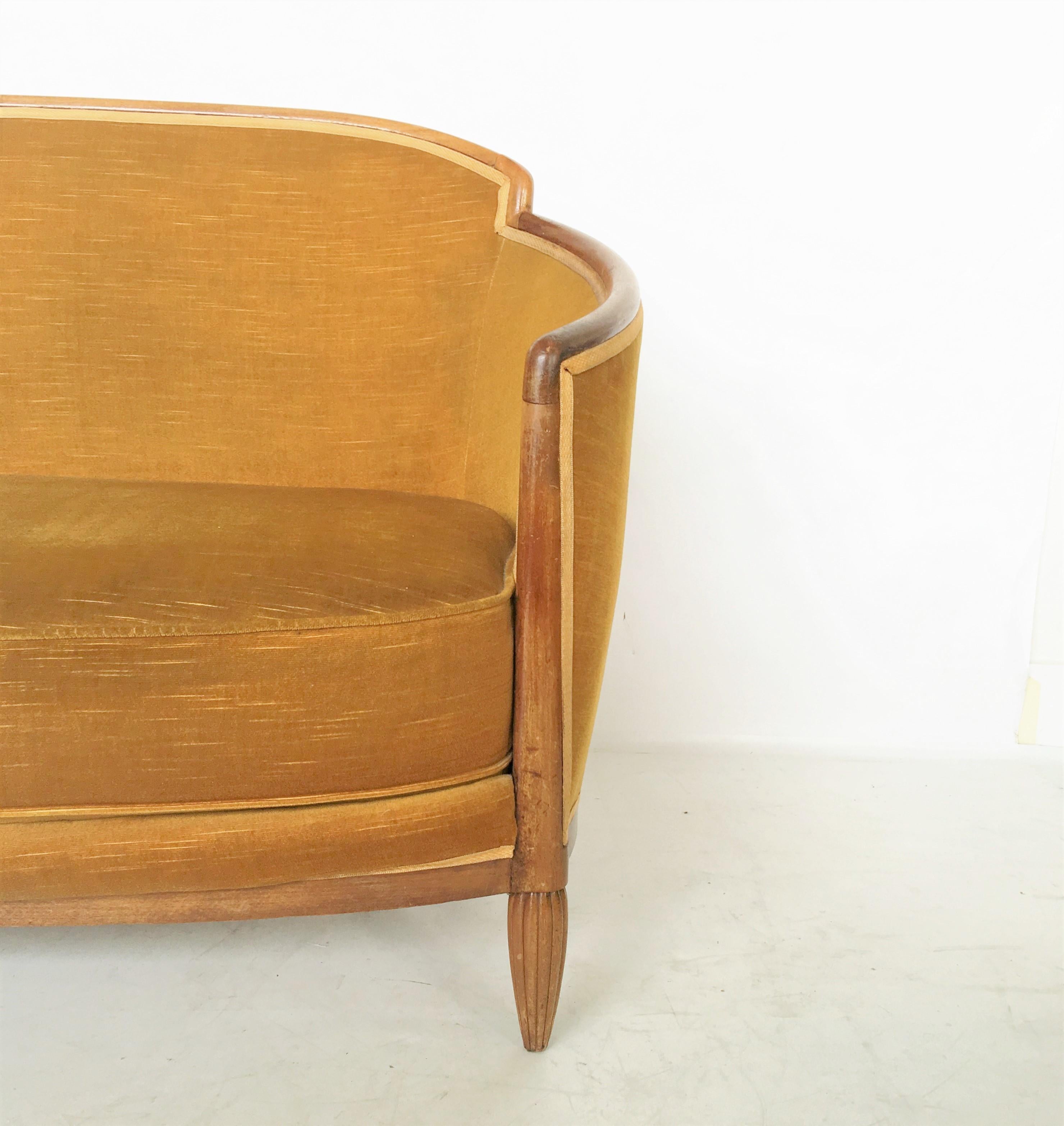 Gorgeous French Art Deco salon settee designed by the top Art Deco designer Paul Follot, circa 1925. Who combined traditional forms with rich decoration. The settee has a sweeping curved backrest extending over solid armrests and resting on reeded