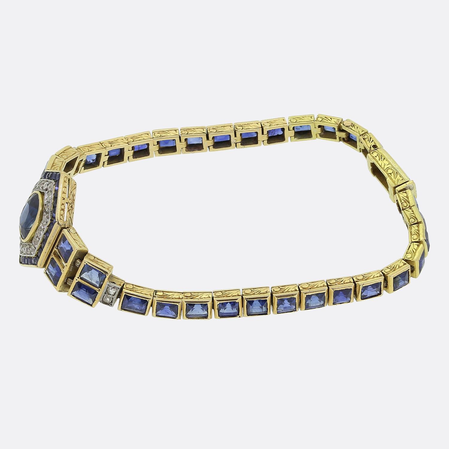 Here we have an exquisite Art Deco sapphire and diamond bracelet. The centrepiece showcases a captivating navy blue sapphire amidst a double frame of round faceted old cut diamonds and square calibrated sapphires around the outer edge. The bracelet