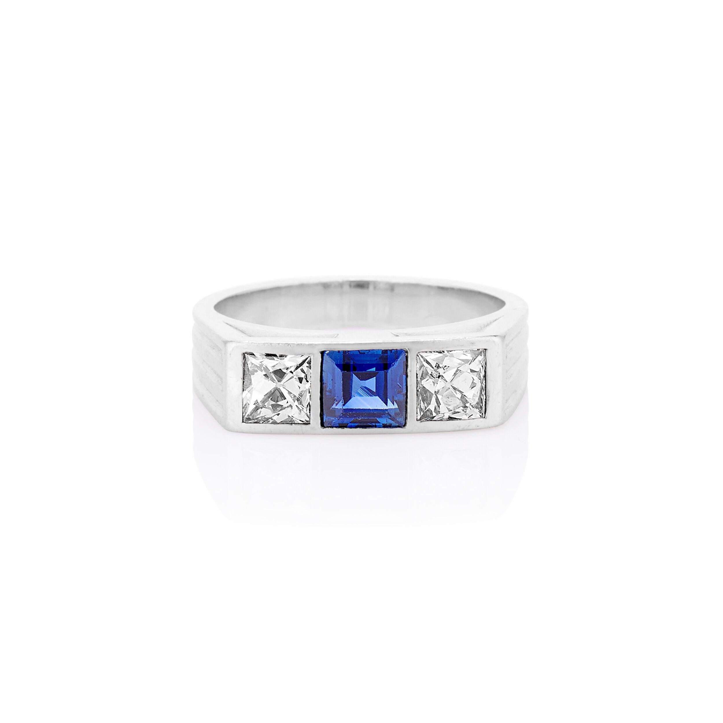 Dieser elegante und raffinierte Drei-Stein-Ring aus den 1930er Jahren ist aus Platin gefertigt. Im Mittelpunkt dieses Rings steht ein strahlend blauer Saphir, der zwischen zwei strahlend weißen Diamanten im französischen Schliff liegt. Absolut