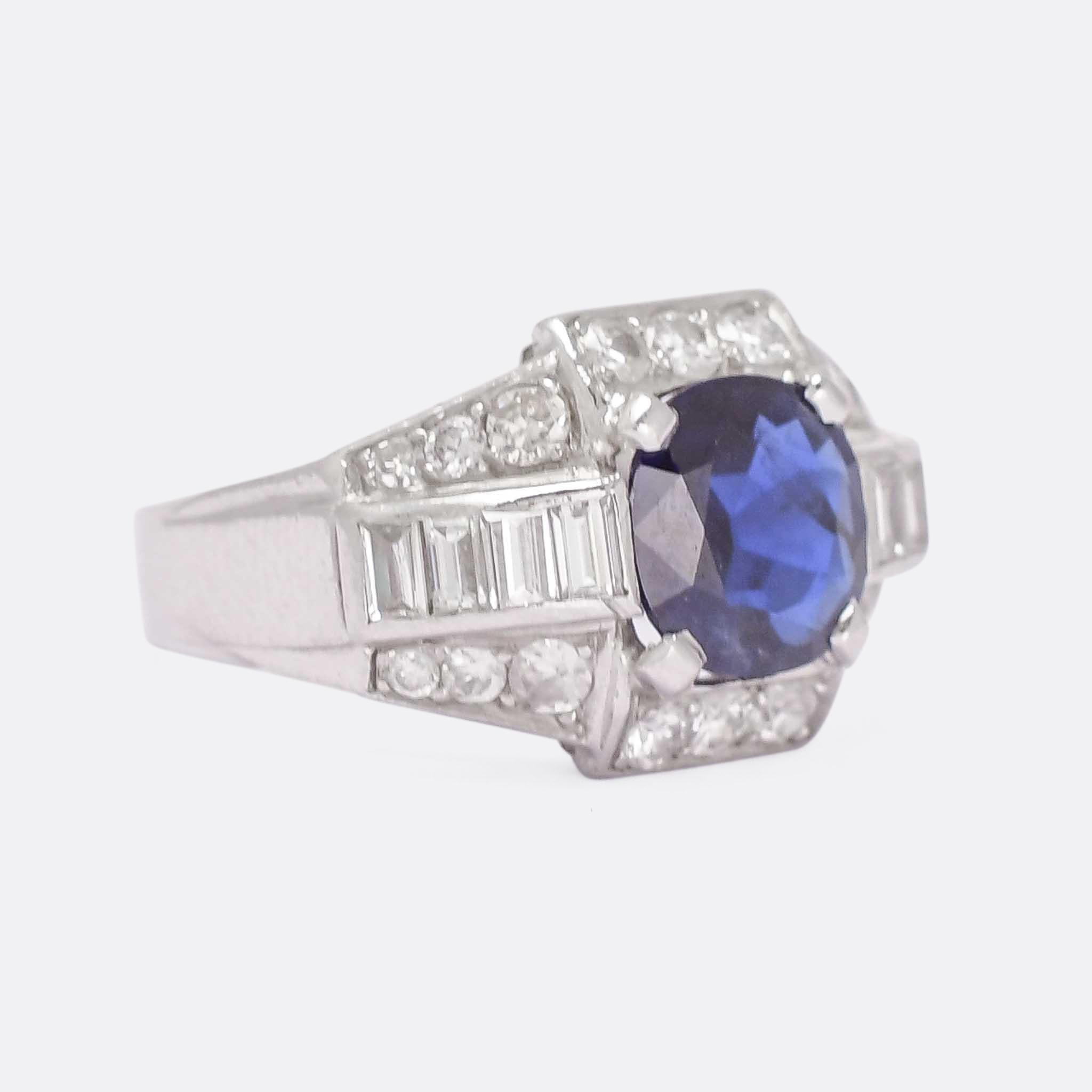 A stunning French Art Deco cocktail ring set with a principal cushion shaped blue sapphire and a combination of baguette and brilliant cut diamonds. The design is bold and very typically late deco, with geometric shapes and lines, while looking