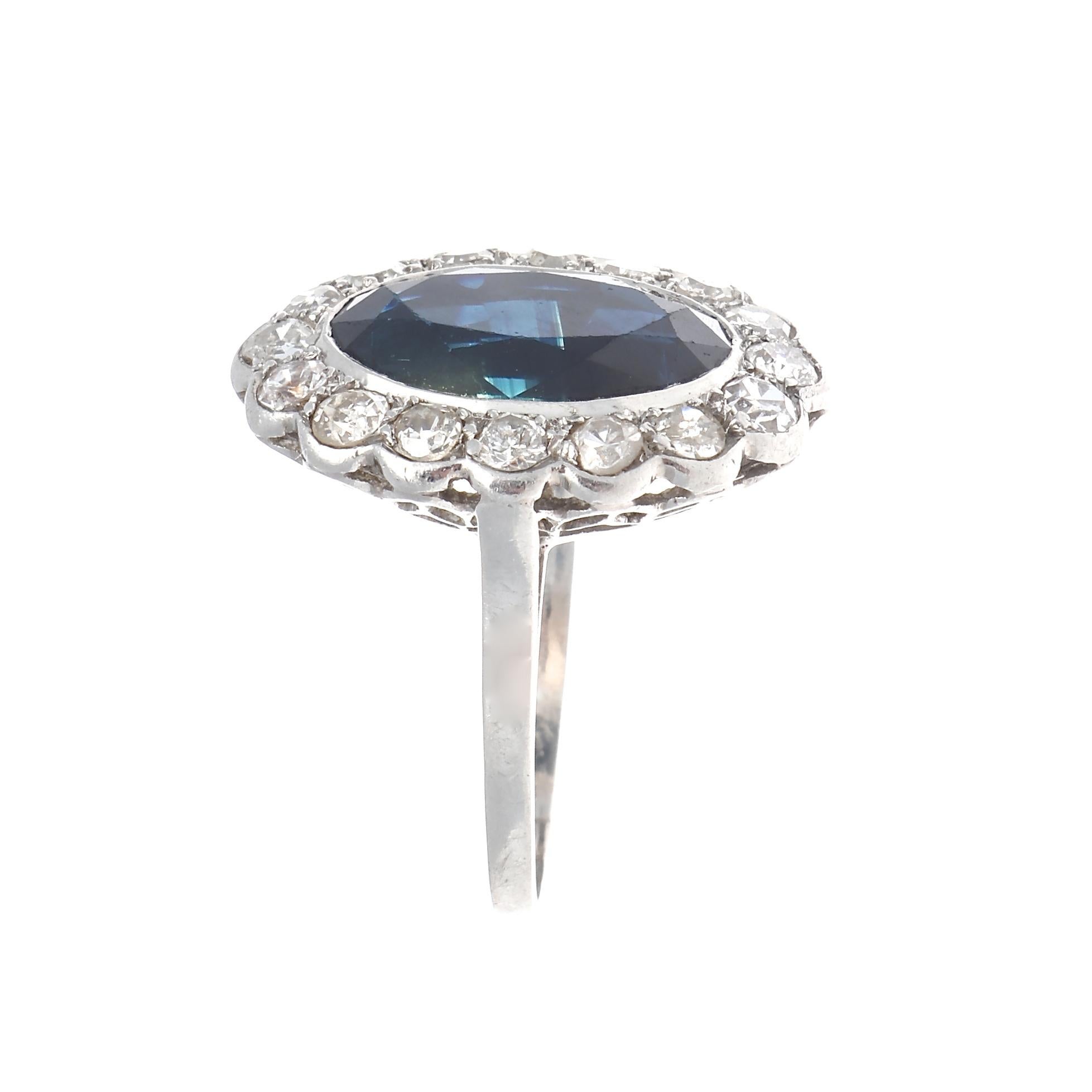 Classical design, culminating into an everyday chic accessory one looks for. Featuring a navy blue oval cut sapphire surrounded by numerous old cut diamond halo. Crafted in platinum. Stamped with French hallmarks. Ring size 5 3/4 and can easily be
