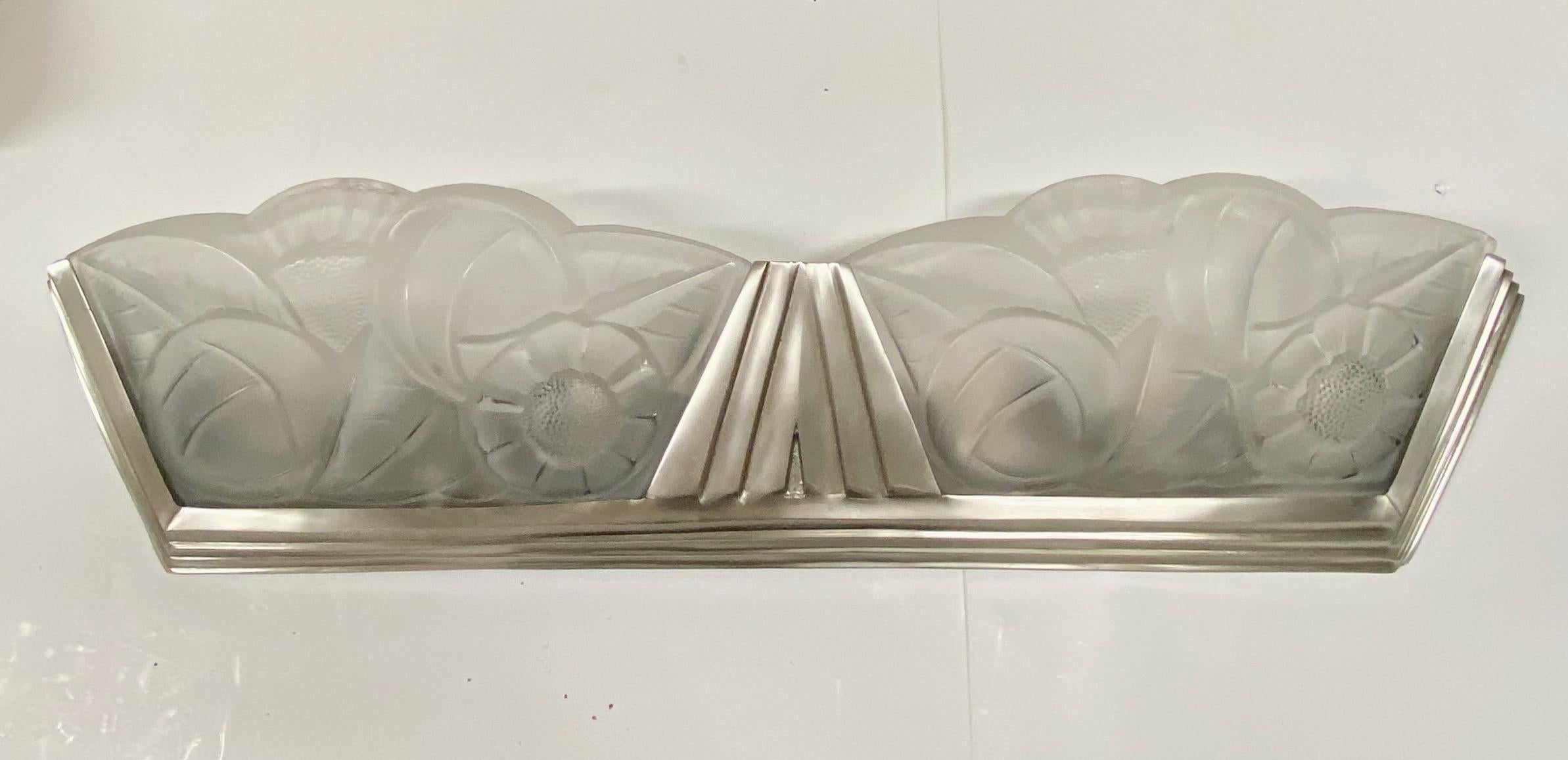 French Art Deco single sconce signed by Degue. Having two clear frosted floral glass panels. Resting in a geometric stepped silver nickel frame. Has been re wired for American use with four candelabra sockets. Each socket has a max watt of 60 wats