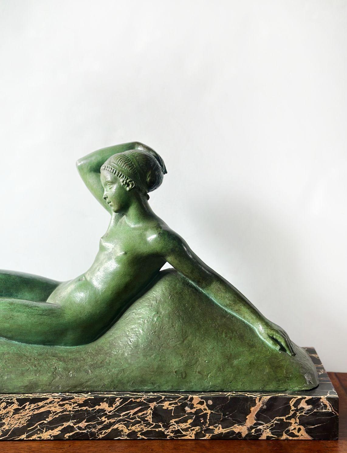 Alluring French Art Deco green patinated bronze sculpture depicting a young nude woman gracefully reclining back while a pair of baby goats are playing with her feet. The rectangular base is made of porto marble. Marked by the artist and foundry