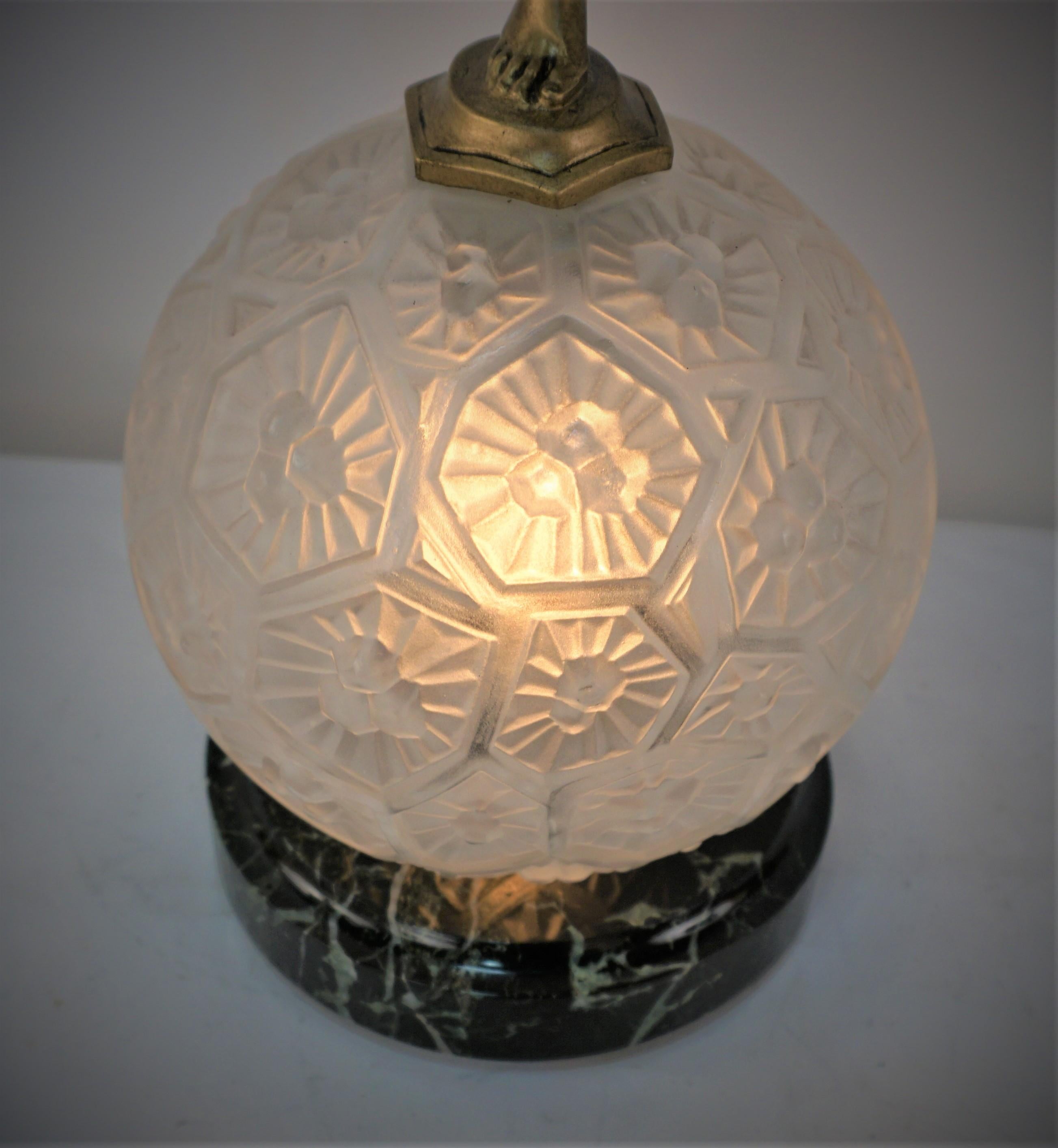 Sculpture of runner on geometric flora glass globe shade with marble base.
