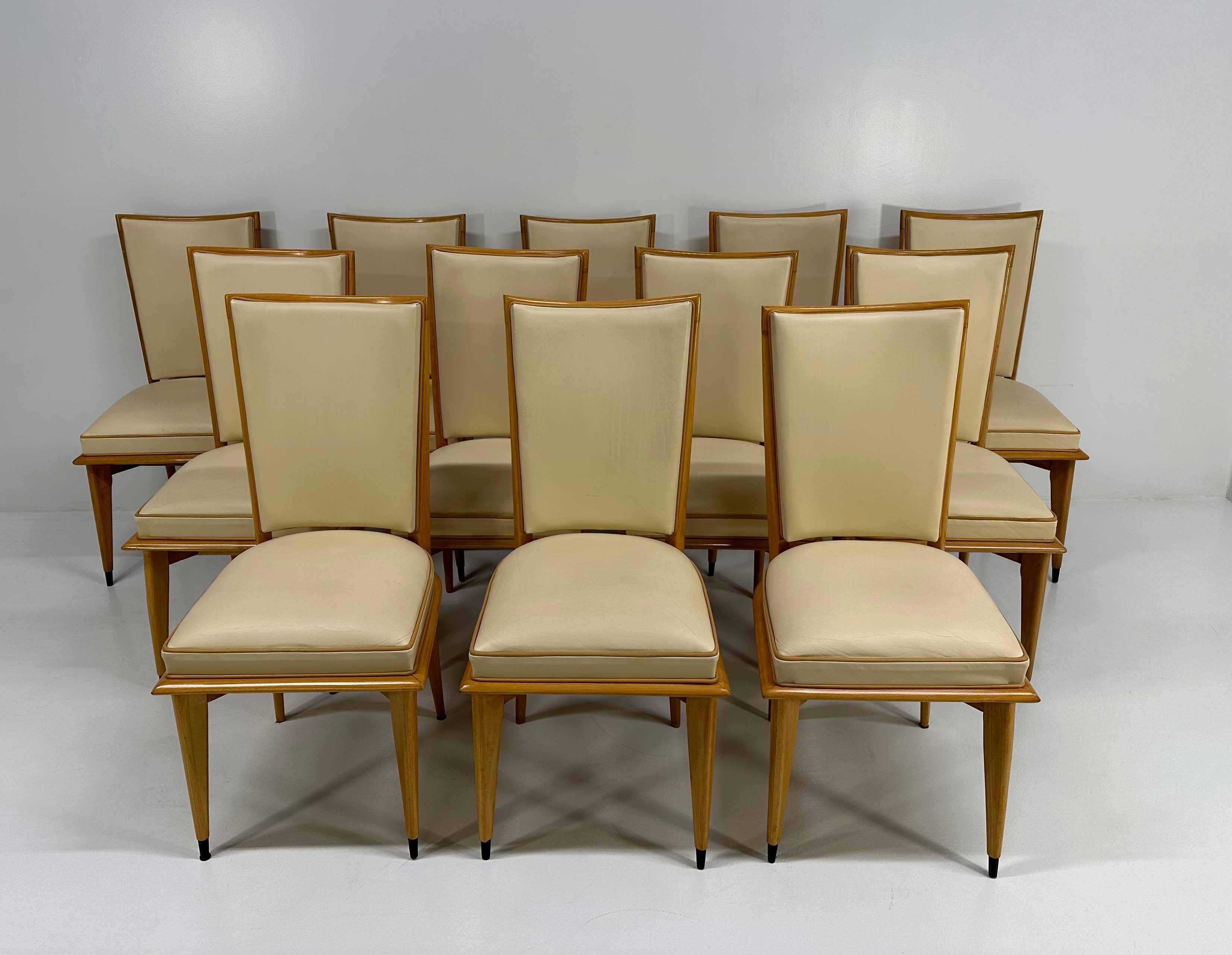 This set of 12 Art Deco chairs was produced in France in the 1930s. They have a maple structure and are upholstered with two different color of leather: cream and light brown for the profiles. 
The tips of the legs are black lacquered.