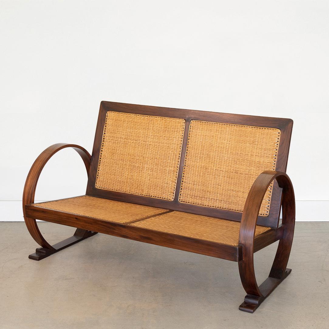 Beautiful Art Deco settee with rosewood arms and frame from France, 1940's. Striking large circular arms and newly woven seat and back with trestle style feet.