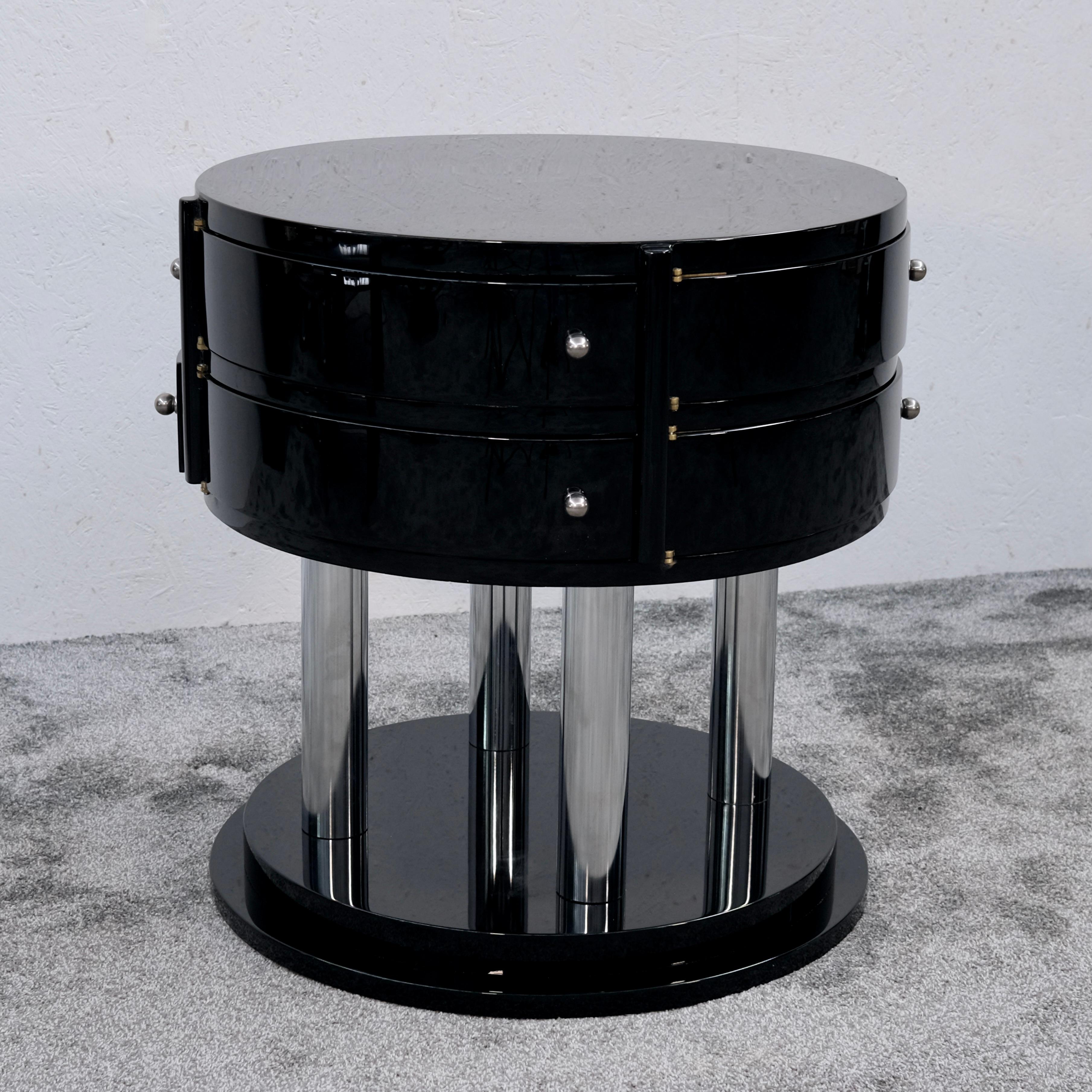 Cette rare table d'appoint Art déco française des années 1930 allie magistralement sophistication fonctionnelle et élégance sculpturale. Son corps rond repose sur un socle étagé, laqué noir, soutenu par quatre colonnes verticales en métal chromé -