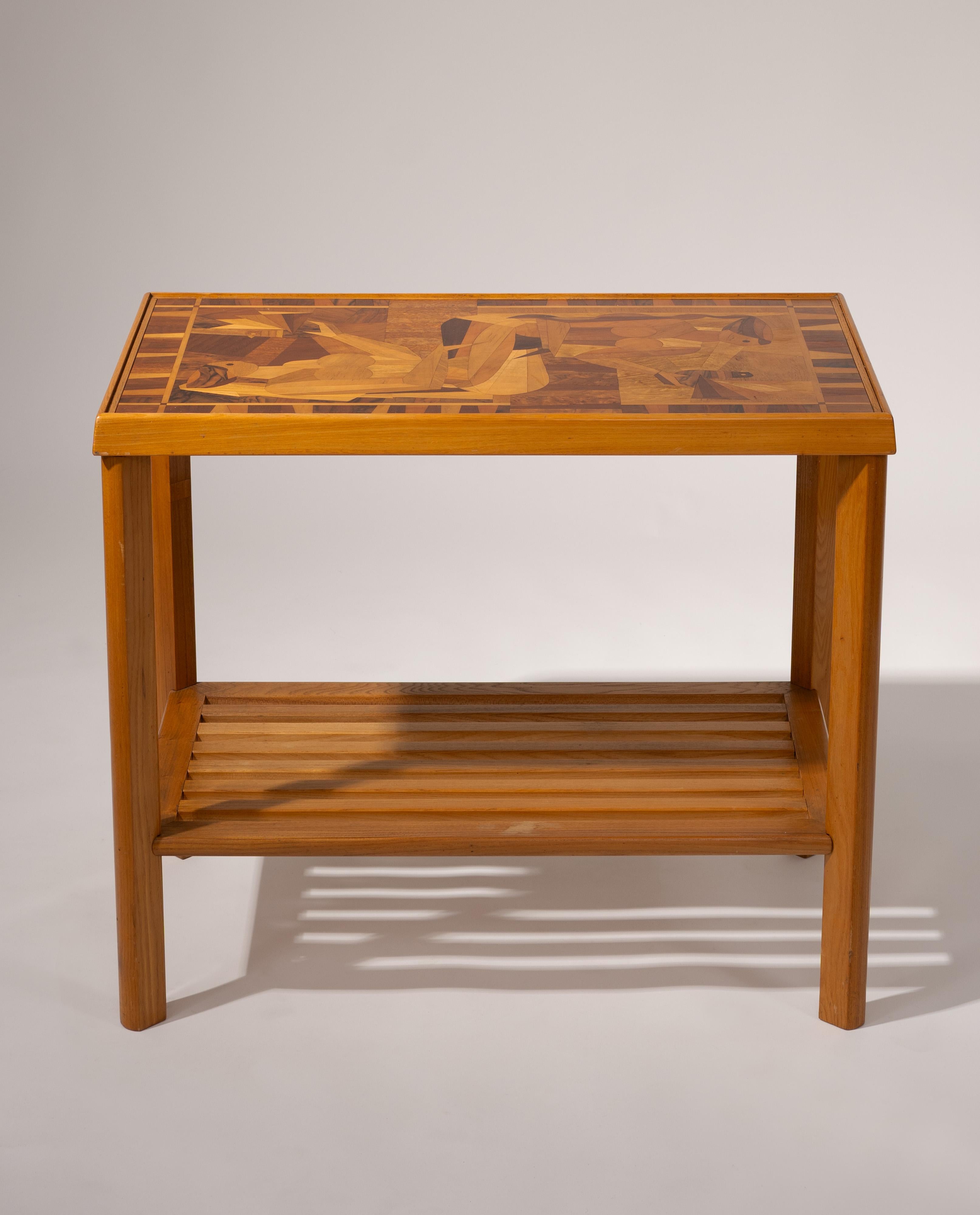 Cette exquise table d'appoint Art déco française, datant des années 1930-1940, présente un extraordinaire plateau en marqueterie représentant deux figures féminines stylisées dans une composition d'inspiration cubiste. Fabriqué à partir d'une riche