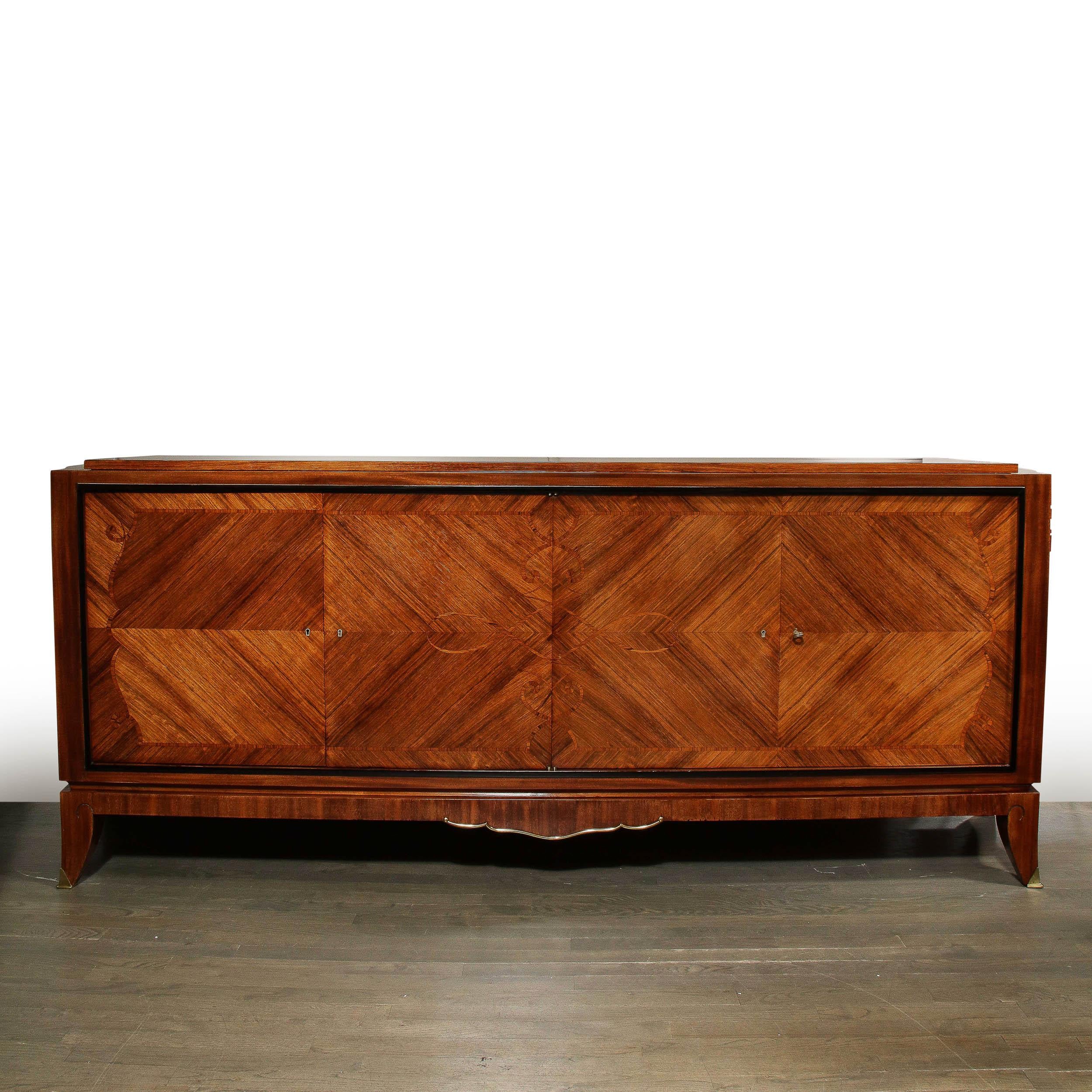 This French Art Deco sideboard was realized in France circa 1940. It features a volumetric rectangular body in bookmatched walnut and lacquer with truly world class marquetry throughout. Sitting on four stylized saber feet with gilded bronze sabots,