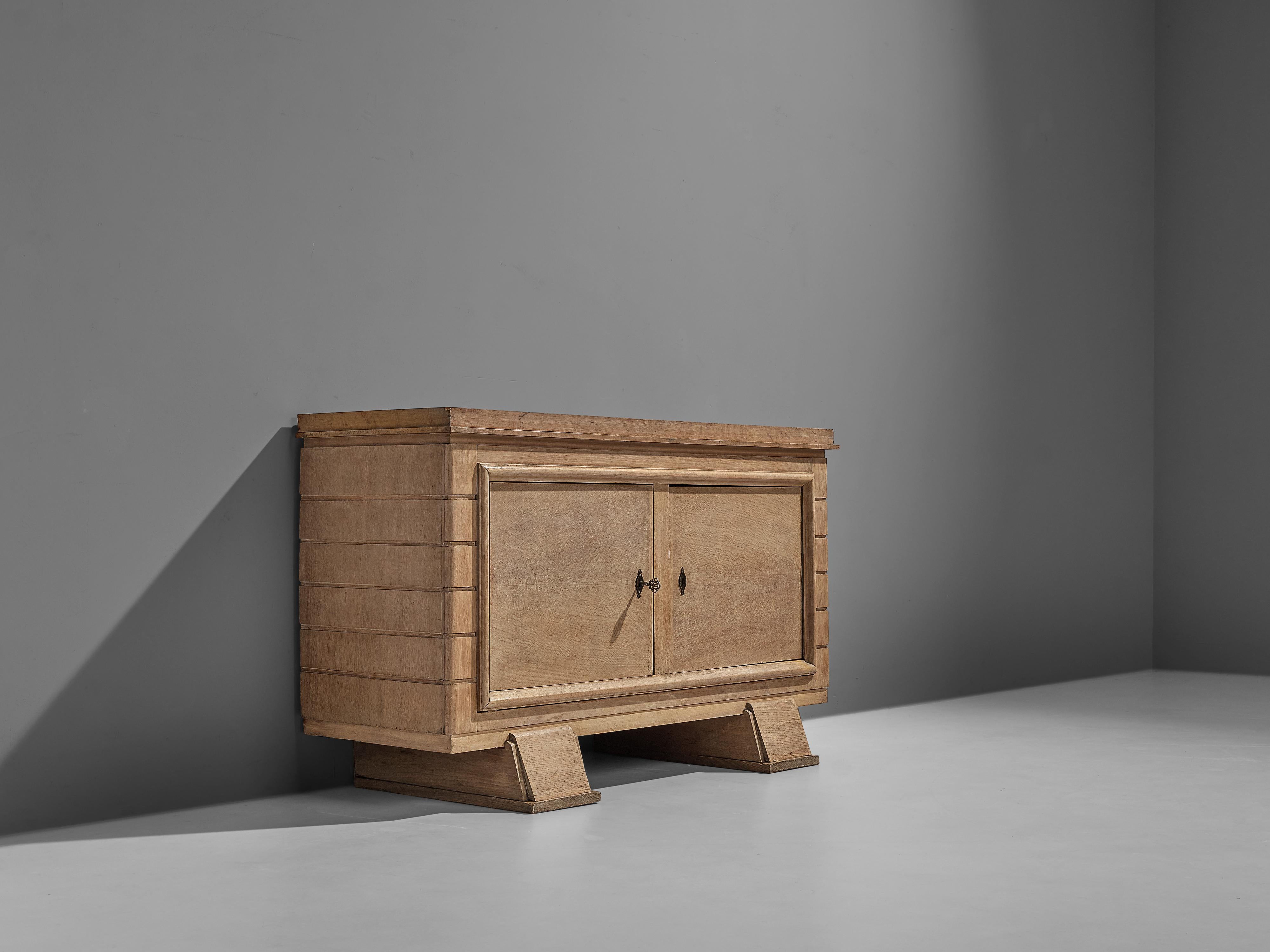 Sideboard, oak, metal, France, 1950s

French Art Deco cabinet in cerused oak. Sturdy sideboard with two sculptural tapered legs which add to the sturdy feeling of the credenza. The sideboard consists of by two doors. The sides of the cabinet are